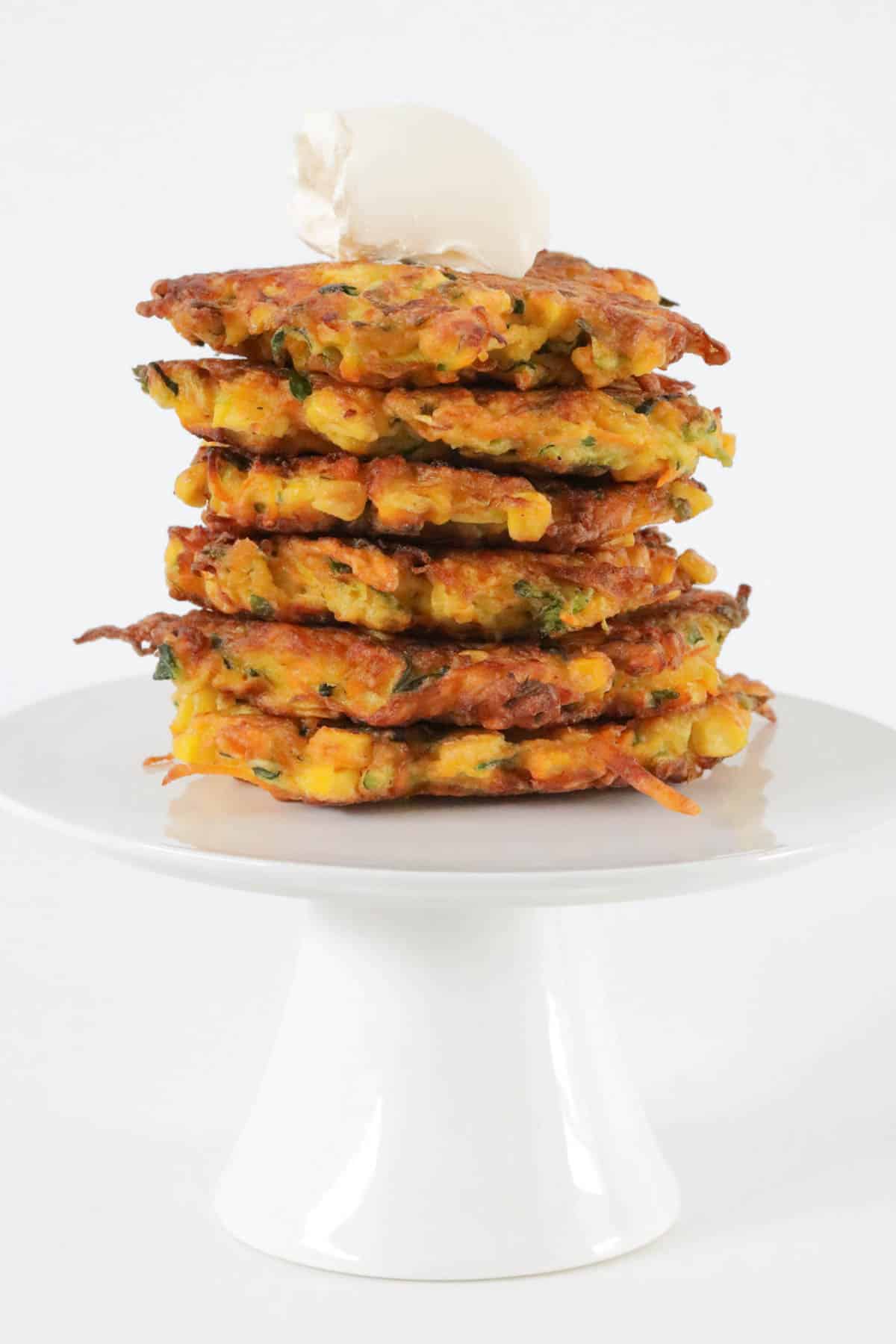 A stack of golden crunchy fritters on a cake stand.