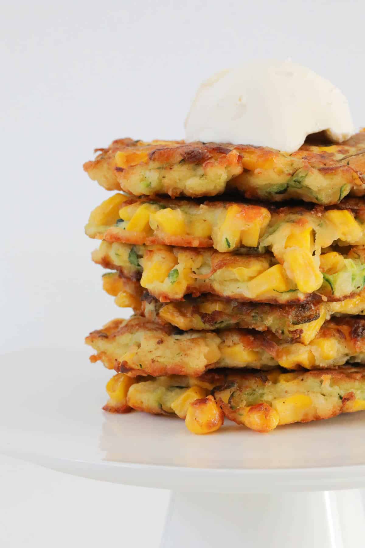 A close up of a stack of veggie patties with sour cream on top.