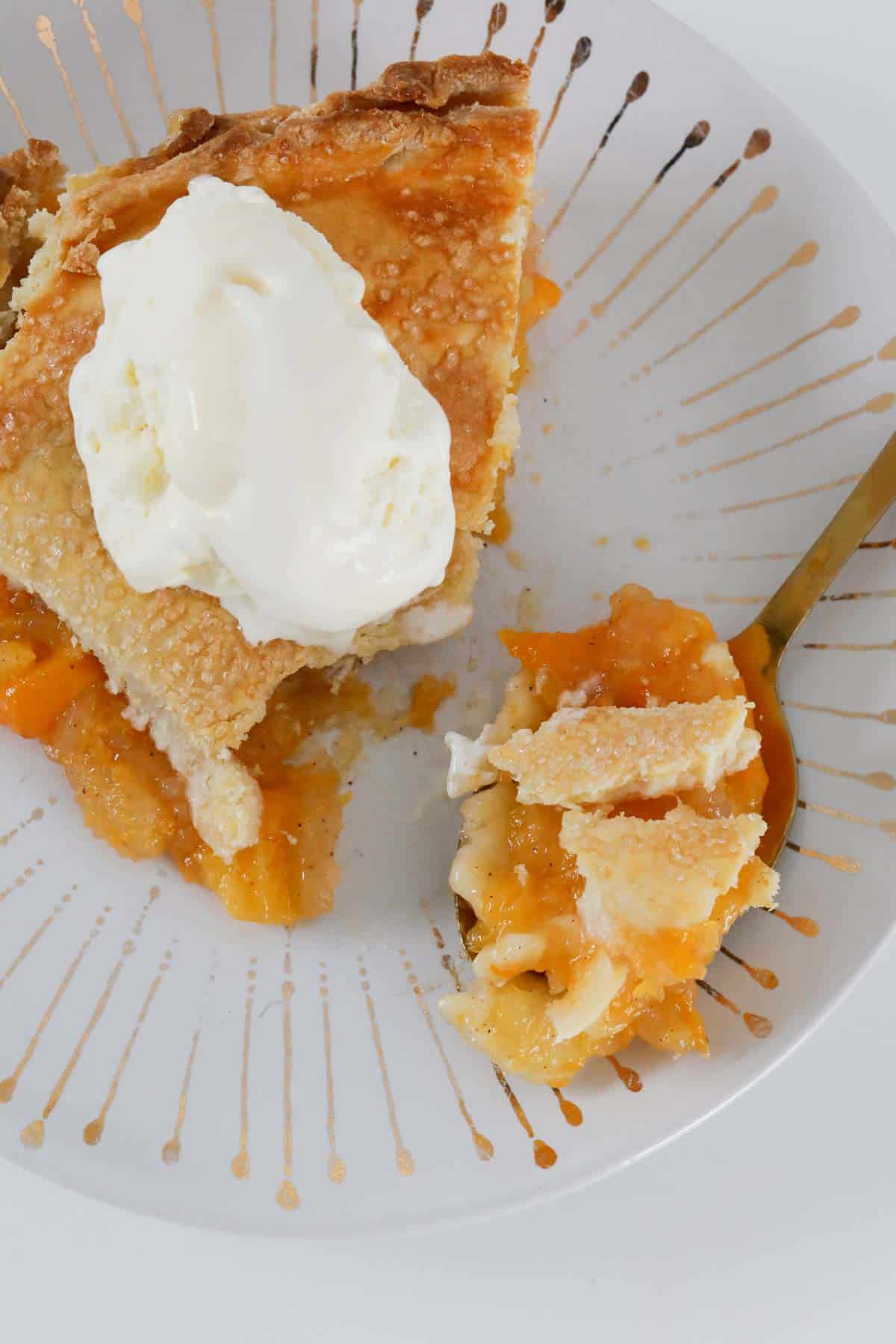 A spoonful of pastry and fruit next to a serve of pie with ice-cream.