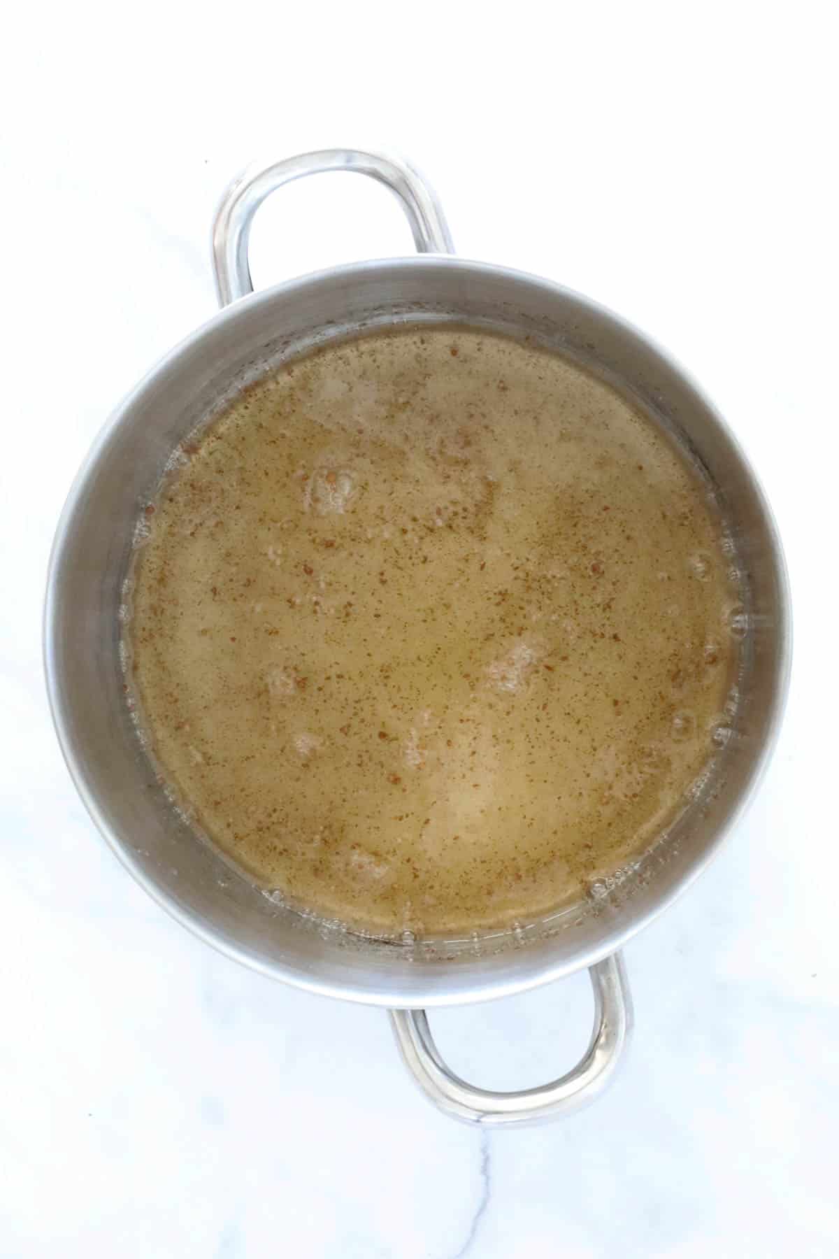 Syrup boiling in a saucepan with lemon juice, cinnamon and sugar.