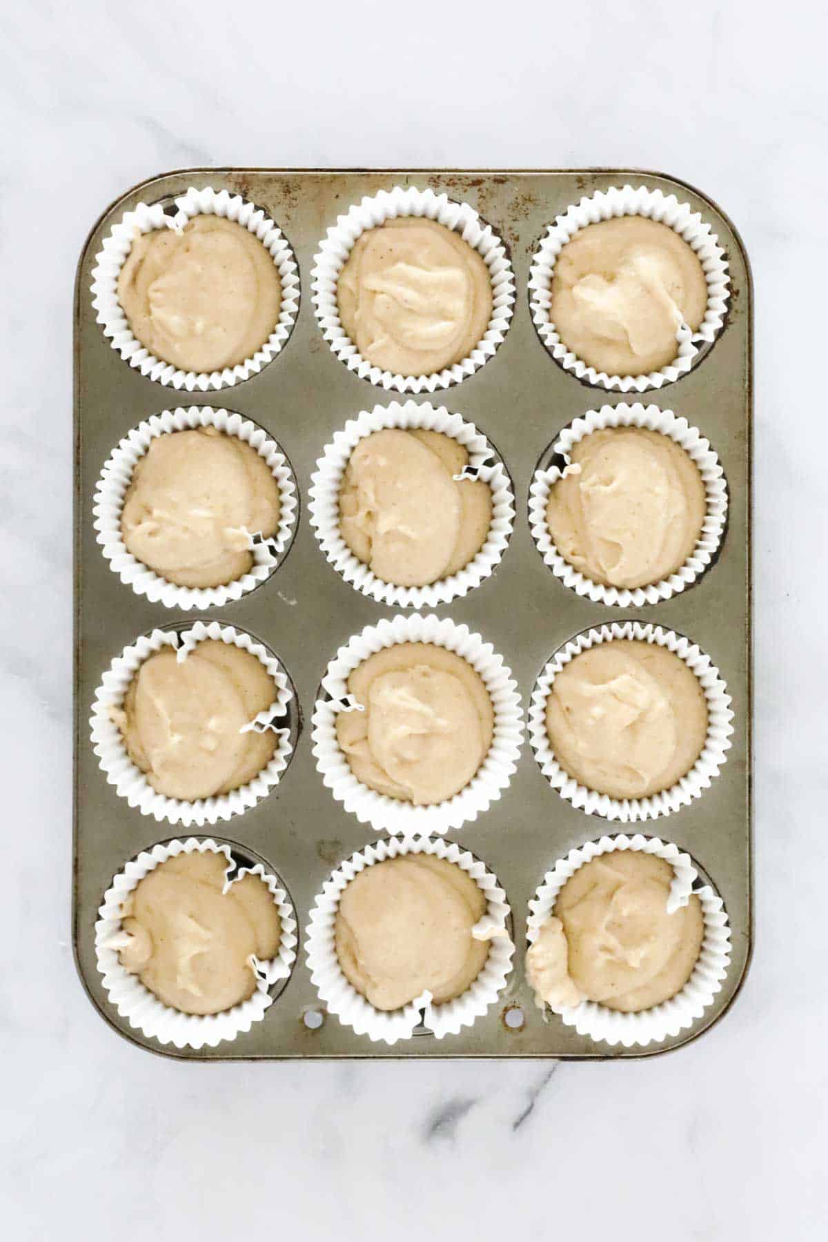 White paper muffin cases filled with banana muffin batter.