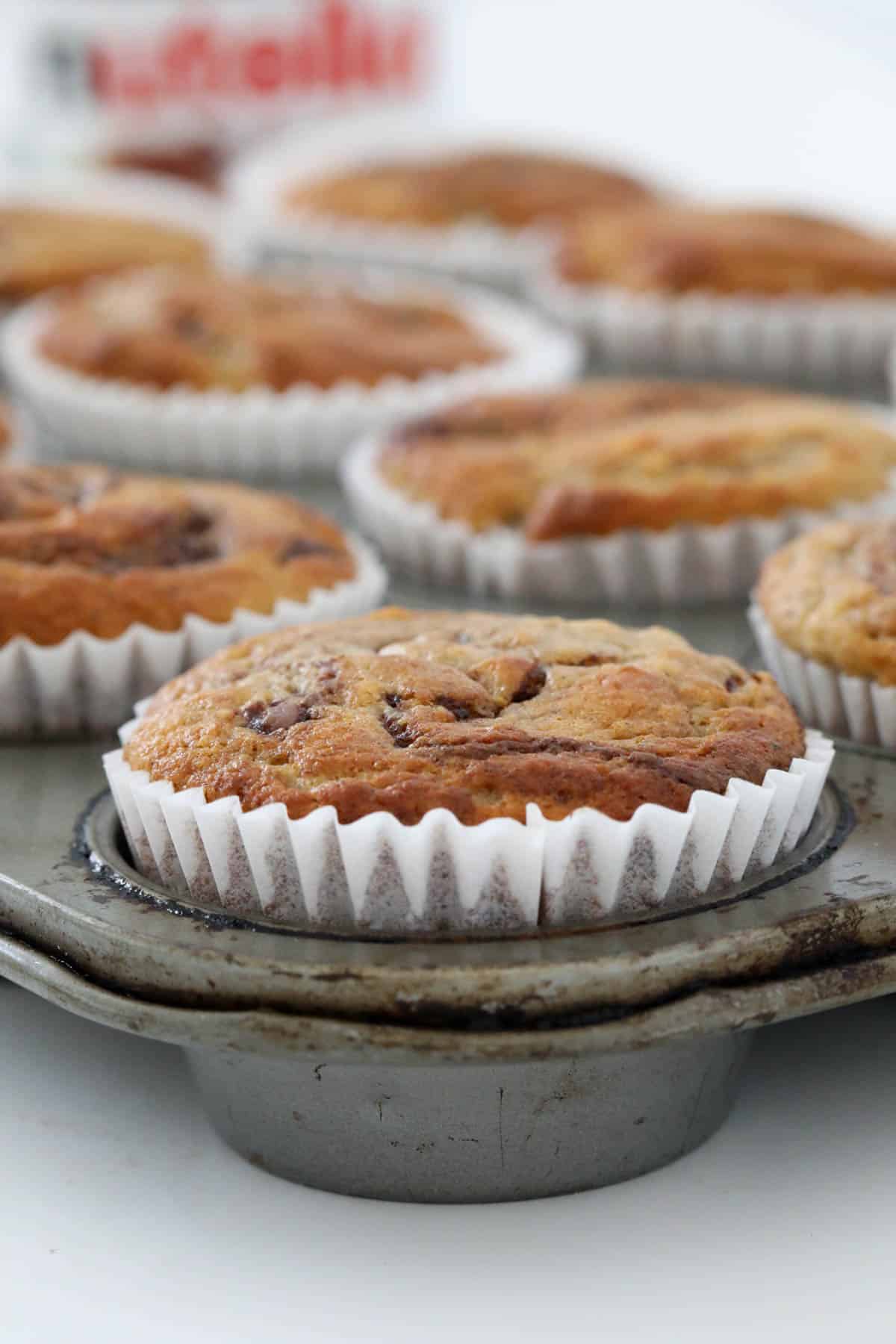 Baked muffins in paper cases in a muffin tray.