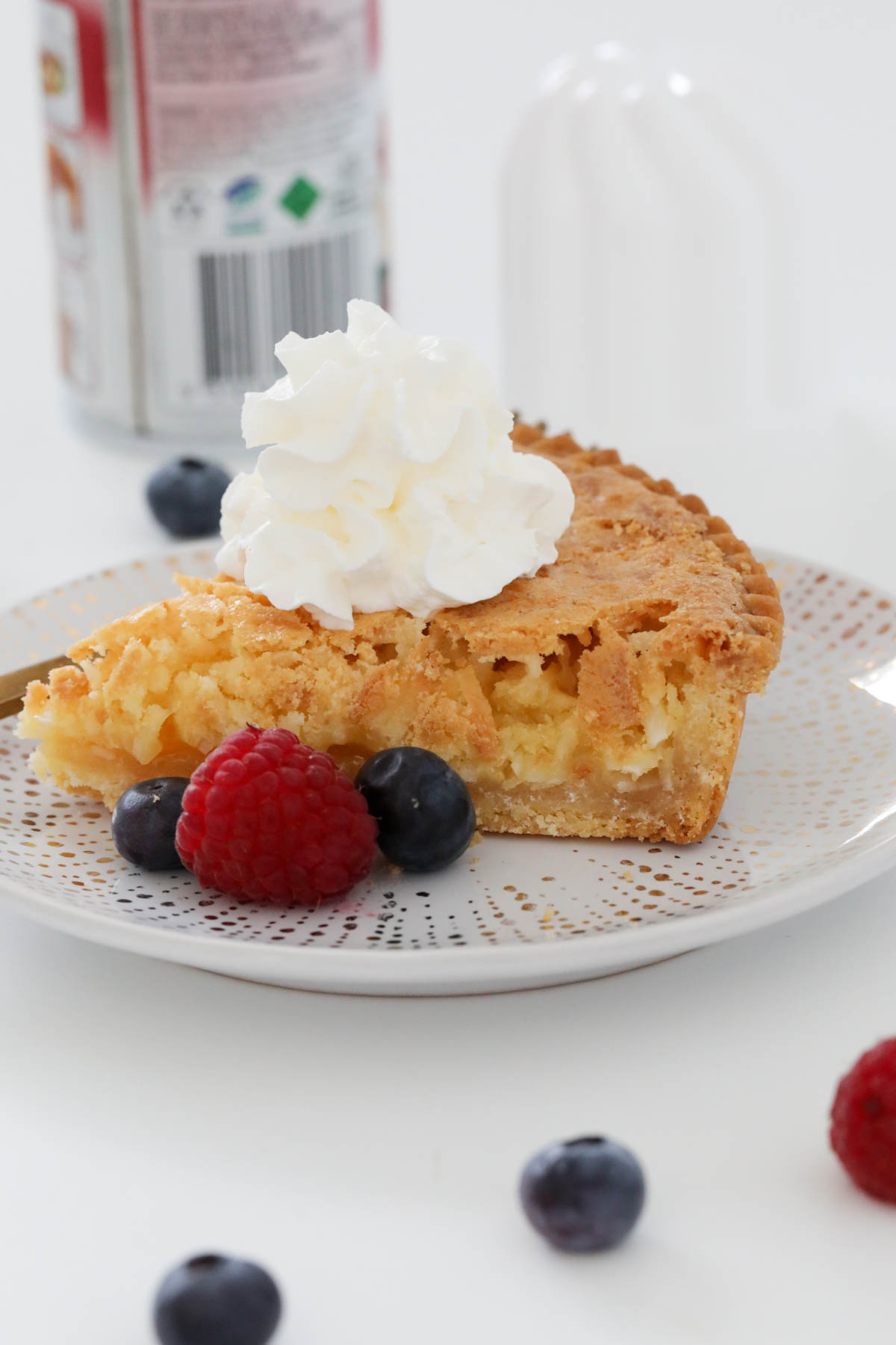 A serve of coconut pie with cream and berries