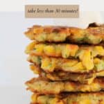 A stack of corn and zucchini fritters with a dollop of sour cream on top.
