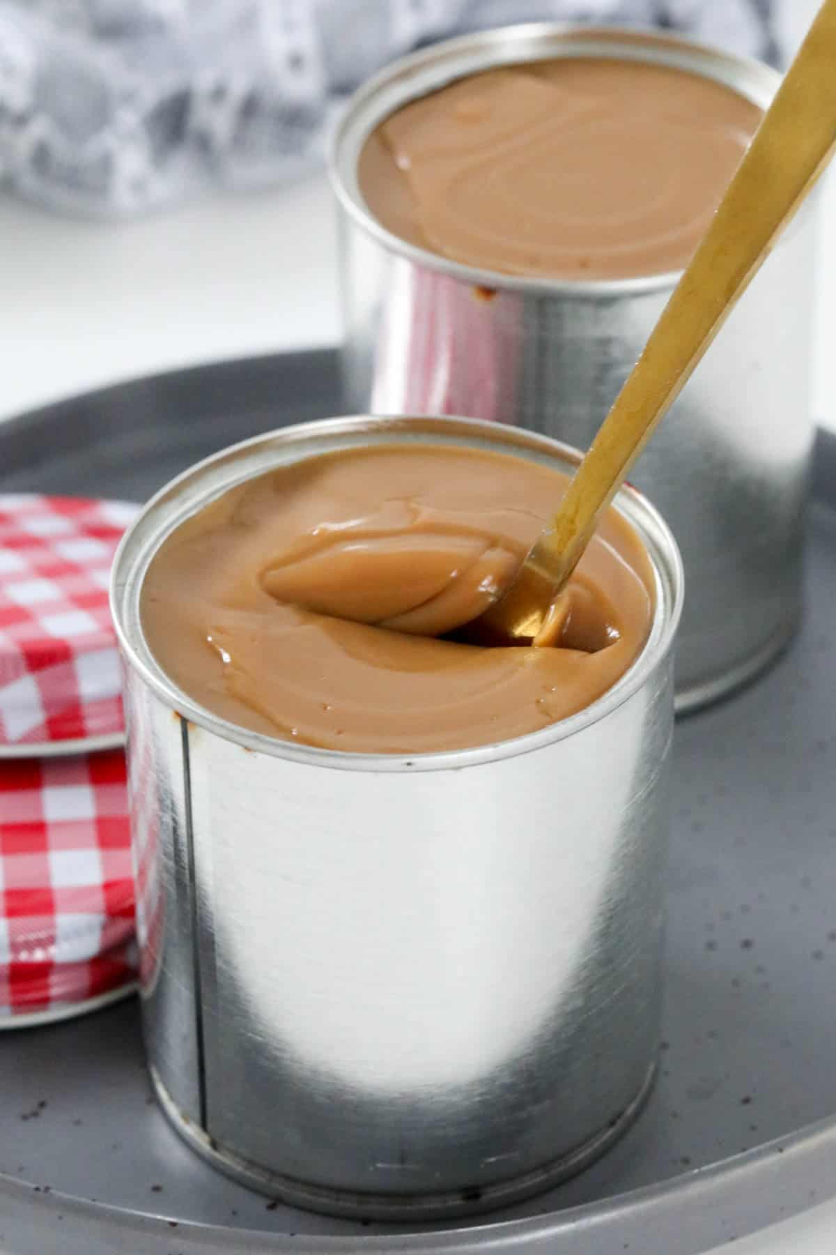 A spoon being dipped into a tin of thick caramel.