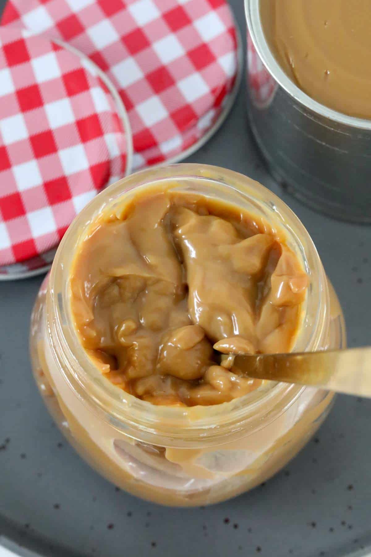 A jar of condensed milk caramel with a spoon in it.