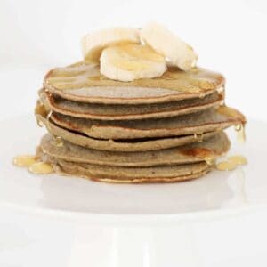 A stack of banana oat pancakes with honey on top.