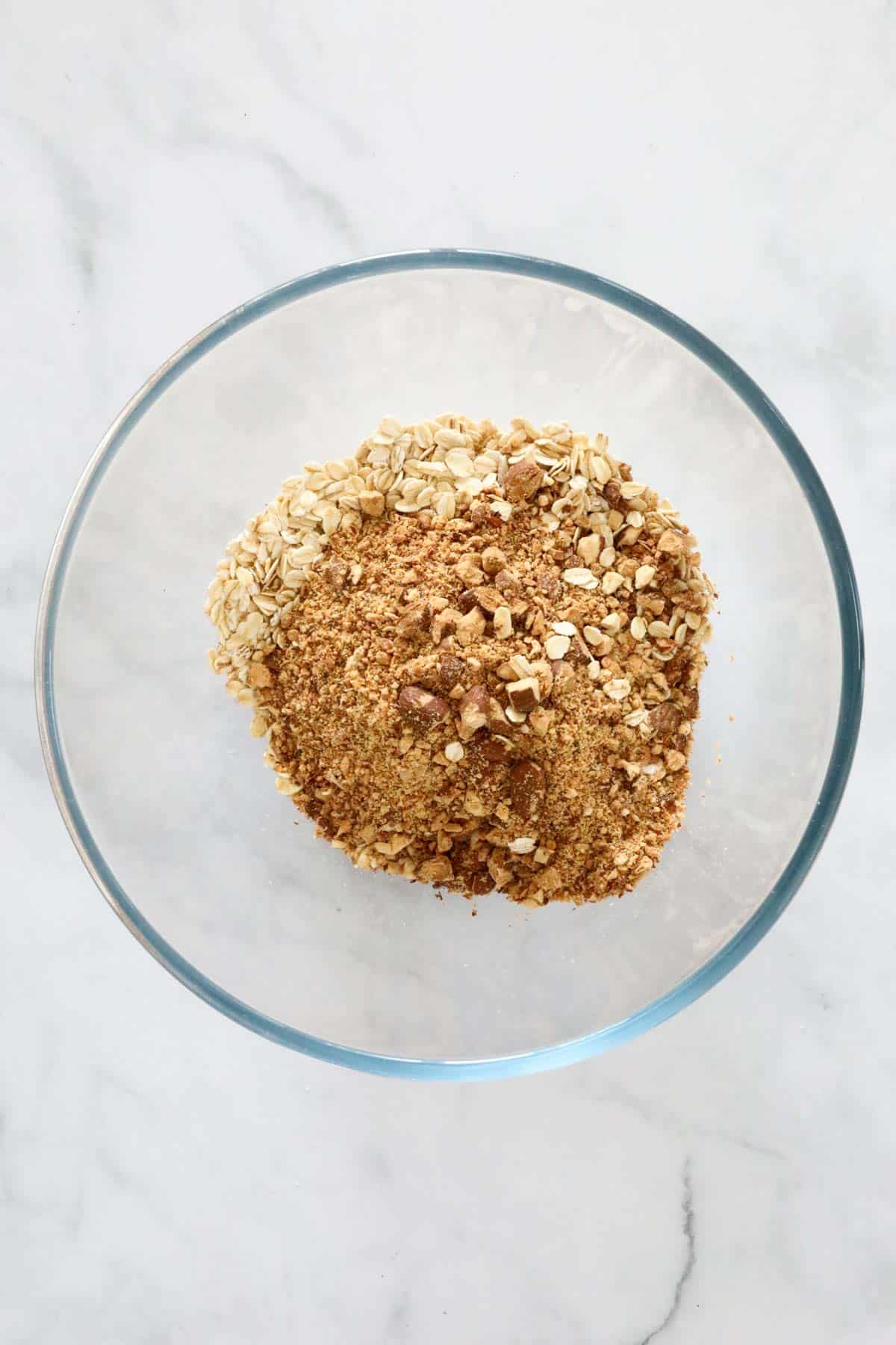 Rolled oats and chopped almonds in a clear glass bowl.