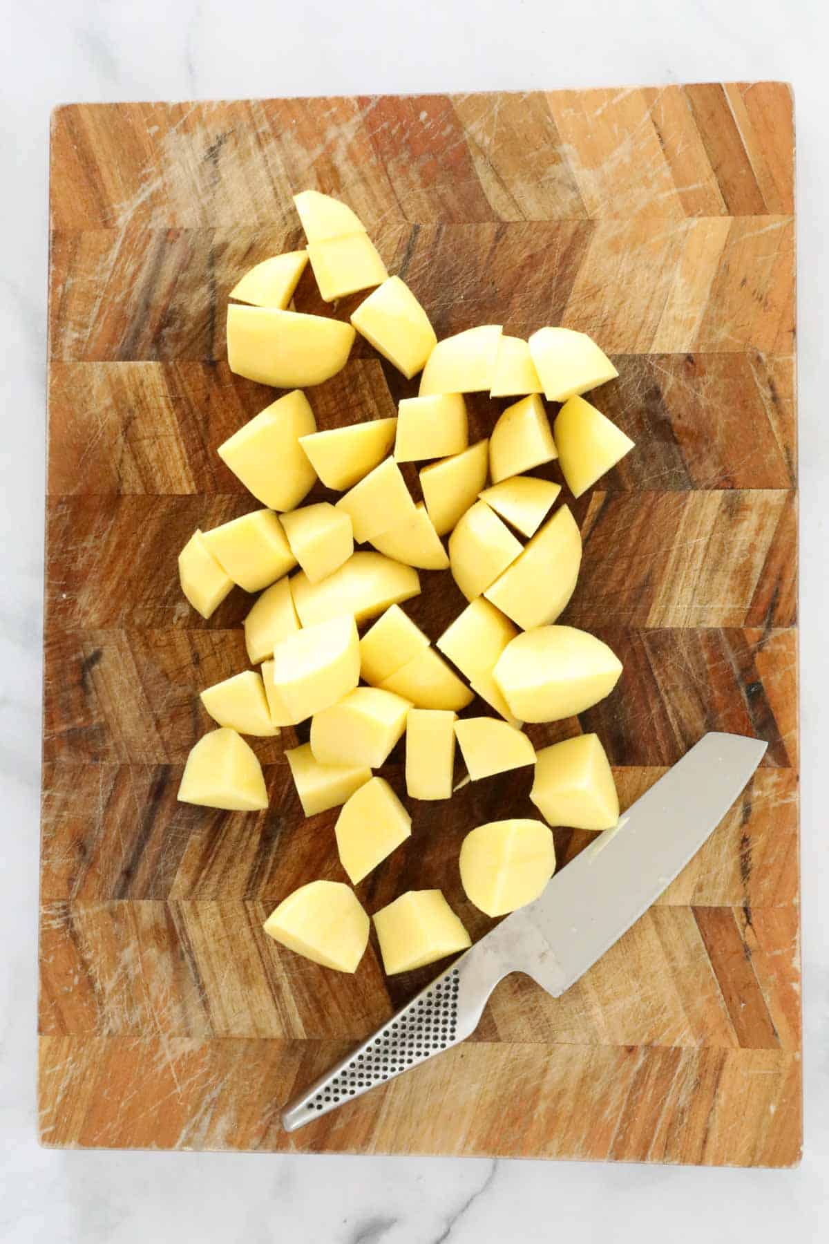 Peeled and chopped potatoes on a chopping board.