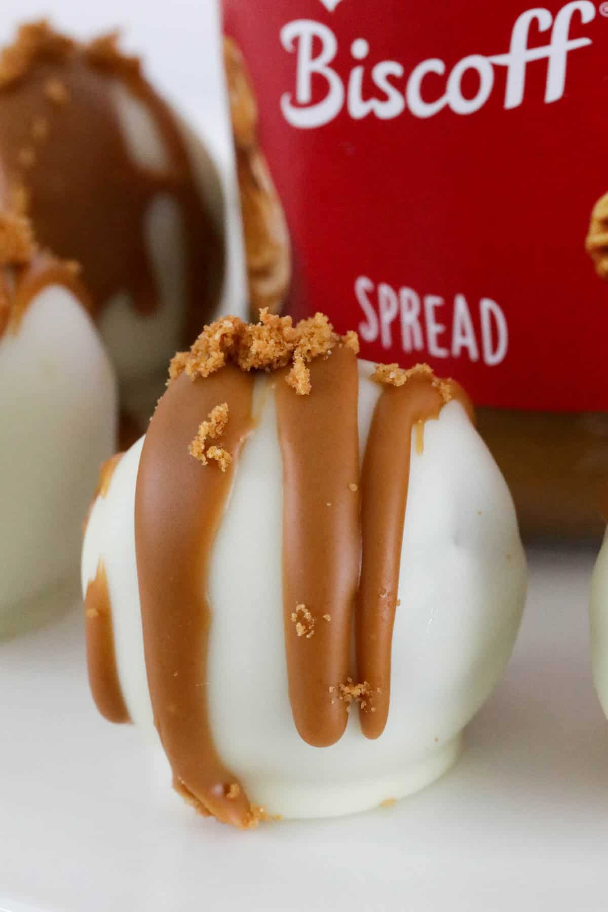 Close up of Biscoff truffle in front of a jar of Lotus Biscoff spread.