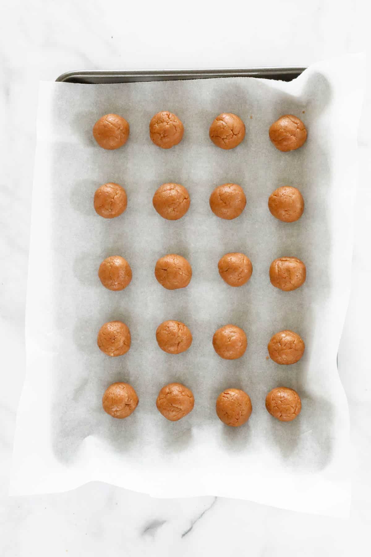 Rolled balls placed on a tray lined with baking paper.