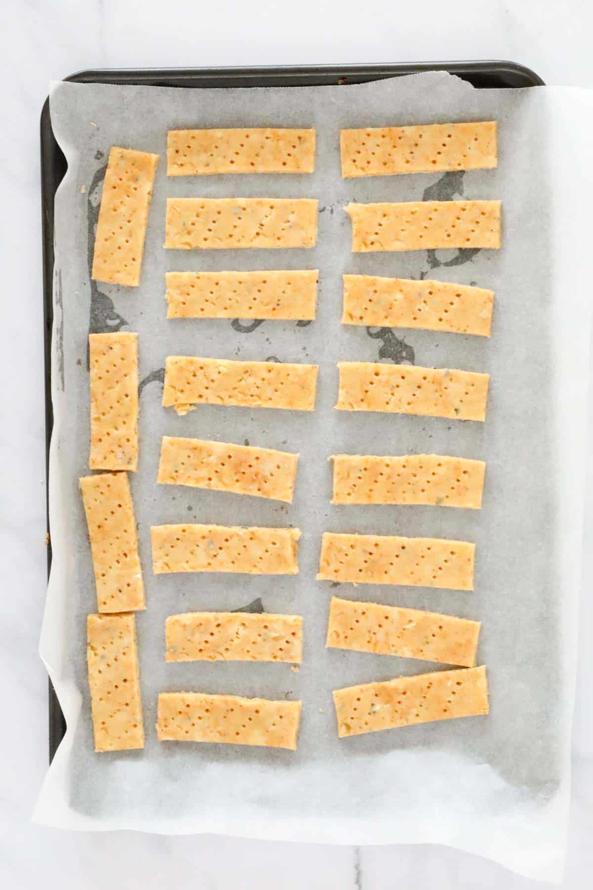 Cheese sticks placed on a lined baking tray.