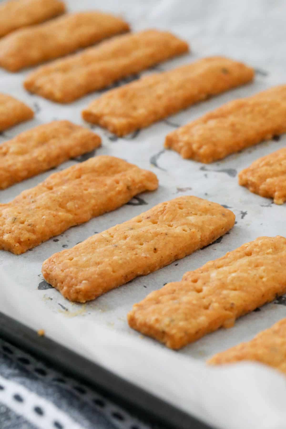 baked cheese sticks on a lined baking tray.