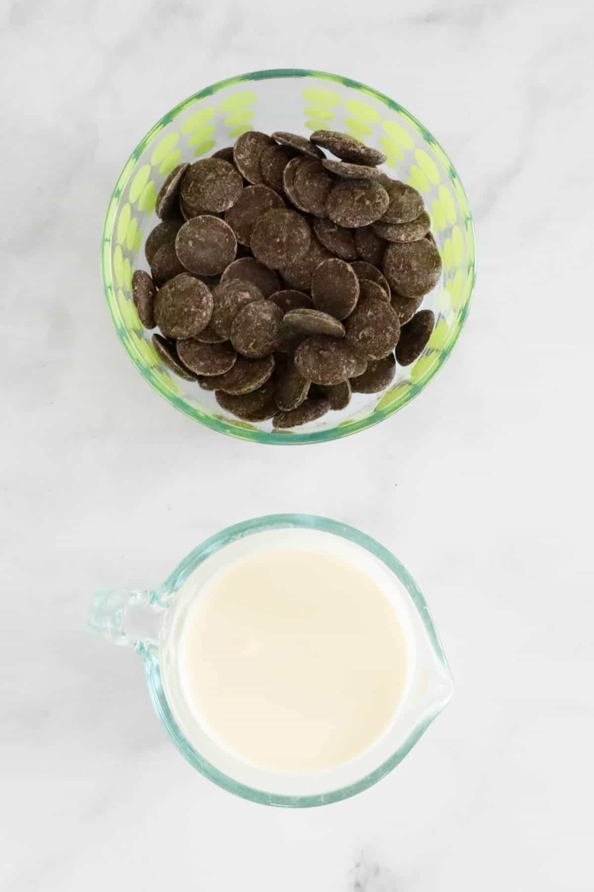 A bowl of chocolate buttons and a bowl of cream to make the chocolate ganache.