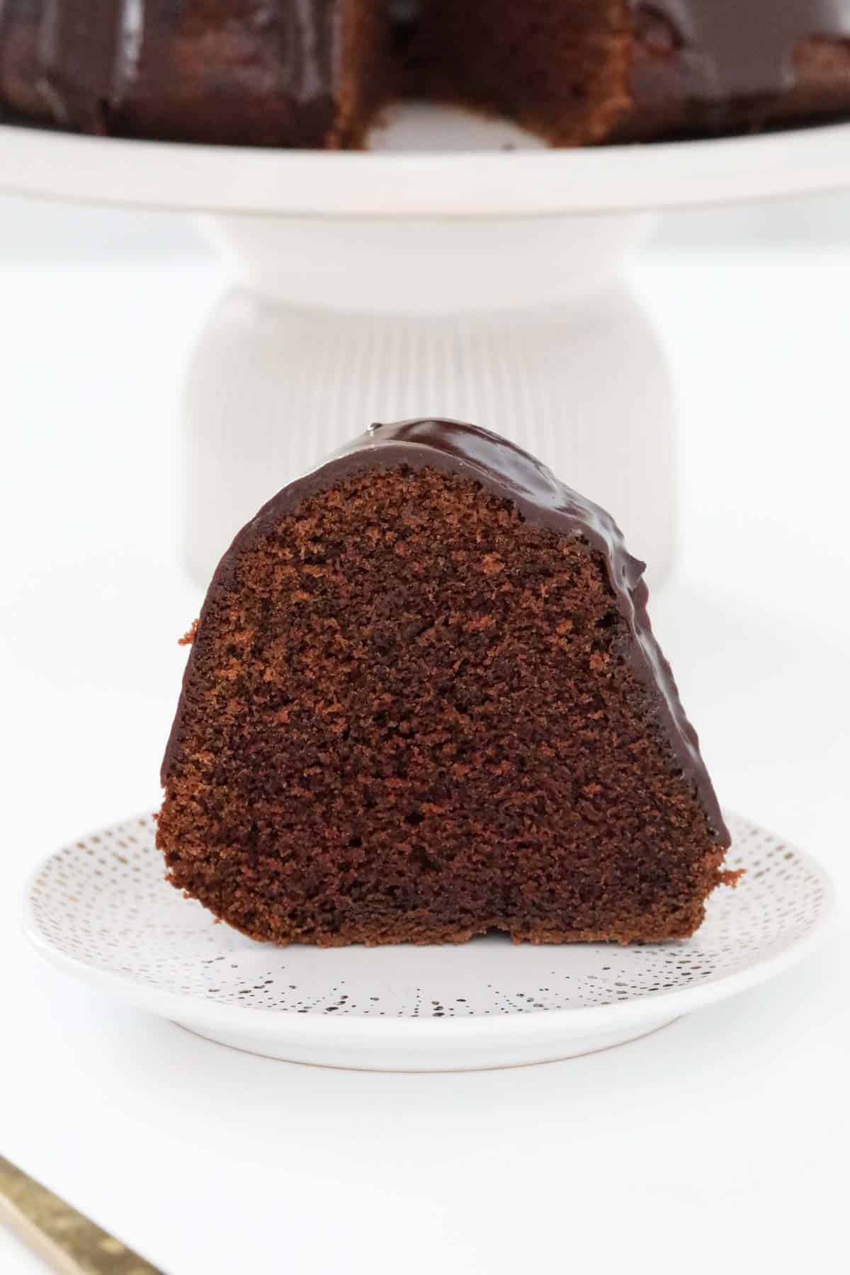A slice of sour cream chocolate cake on a plate to show the texture of the cake.