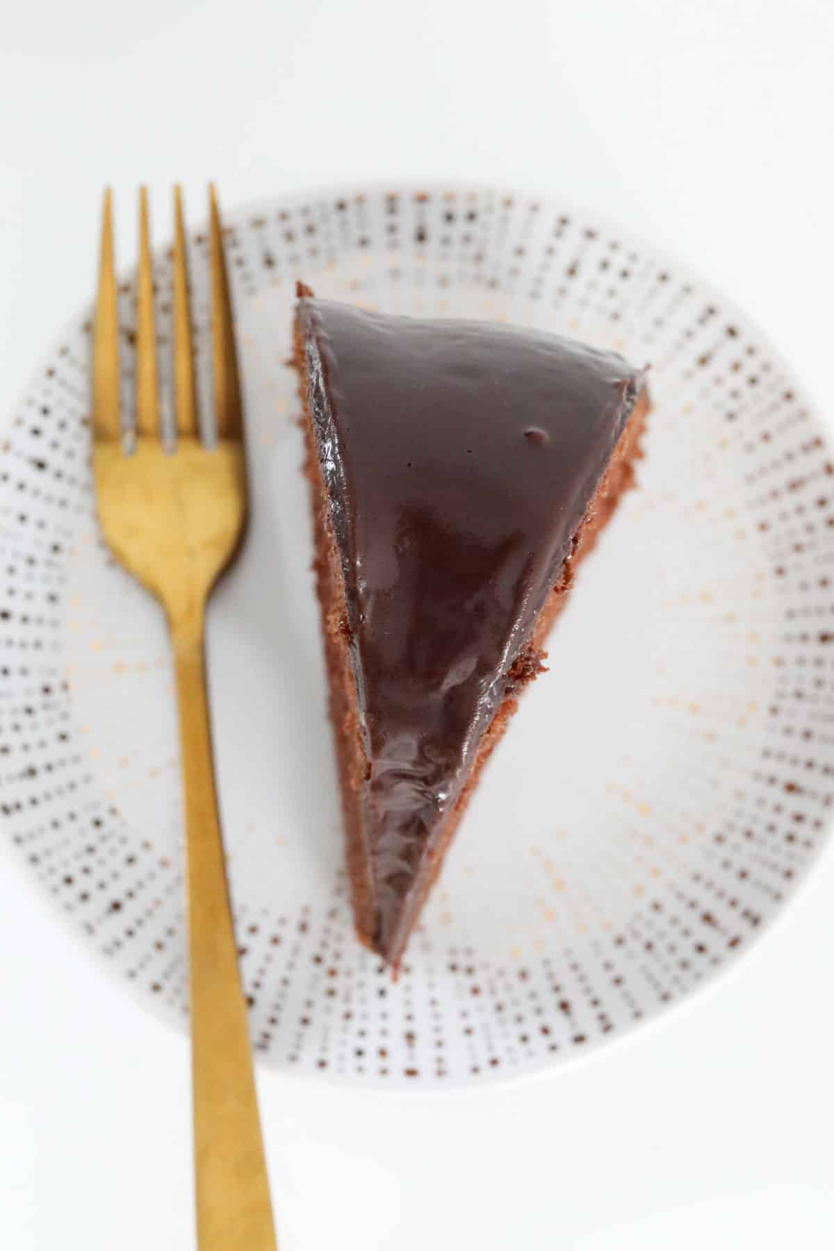 A serve of chocolate pound cake on a plate with a gold fork.