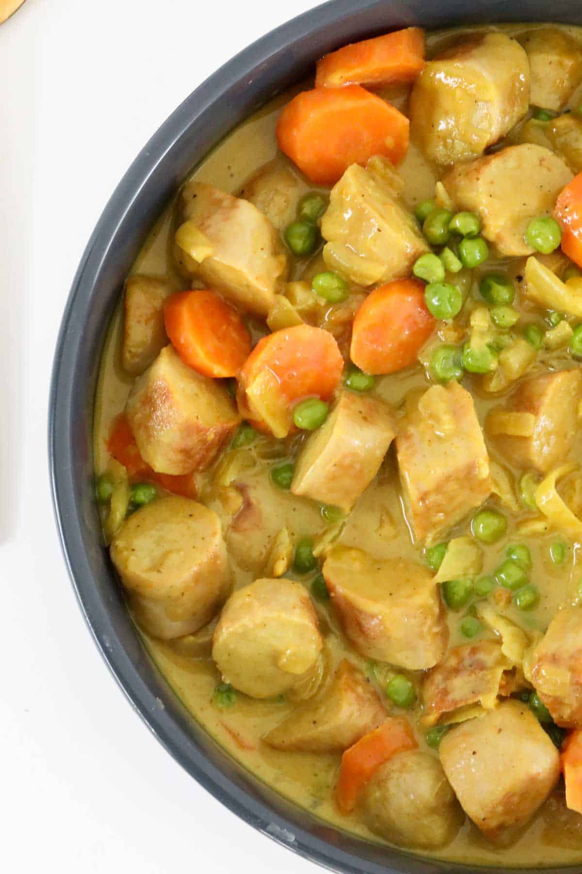 Chunks of sausage, peas and sliced carrot in a gravy .