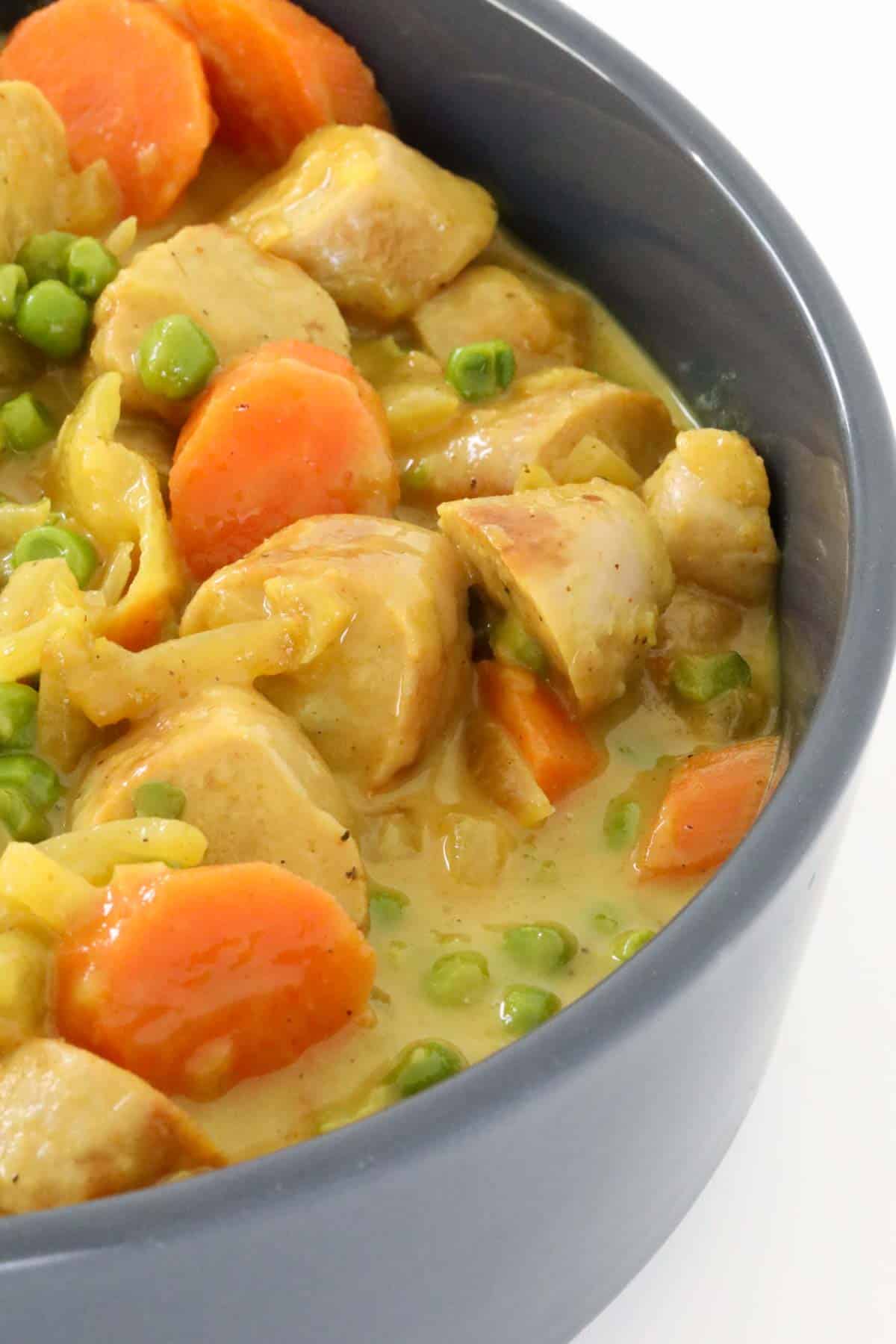 Chunks of sausage in a curried gravy with peas and sliced carrot.