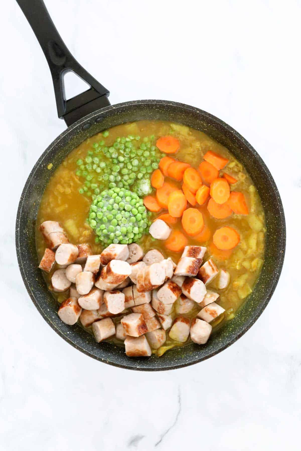 Chunks of sausage, sliced carrot and peas added to the gravy.