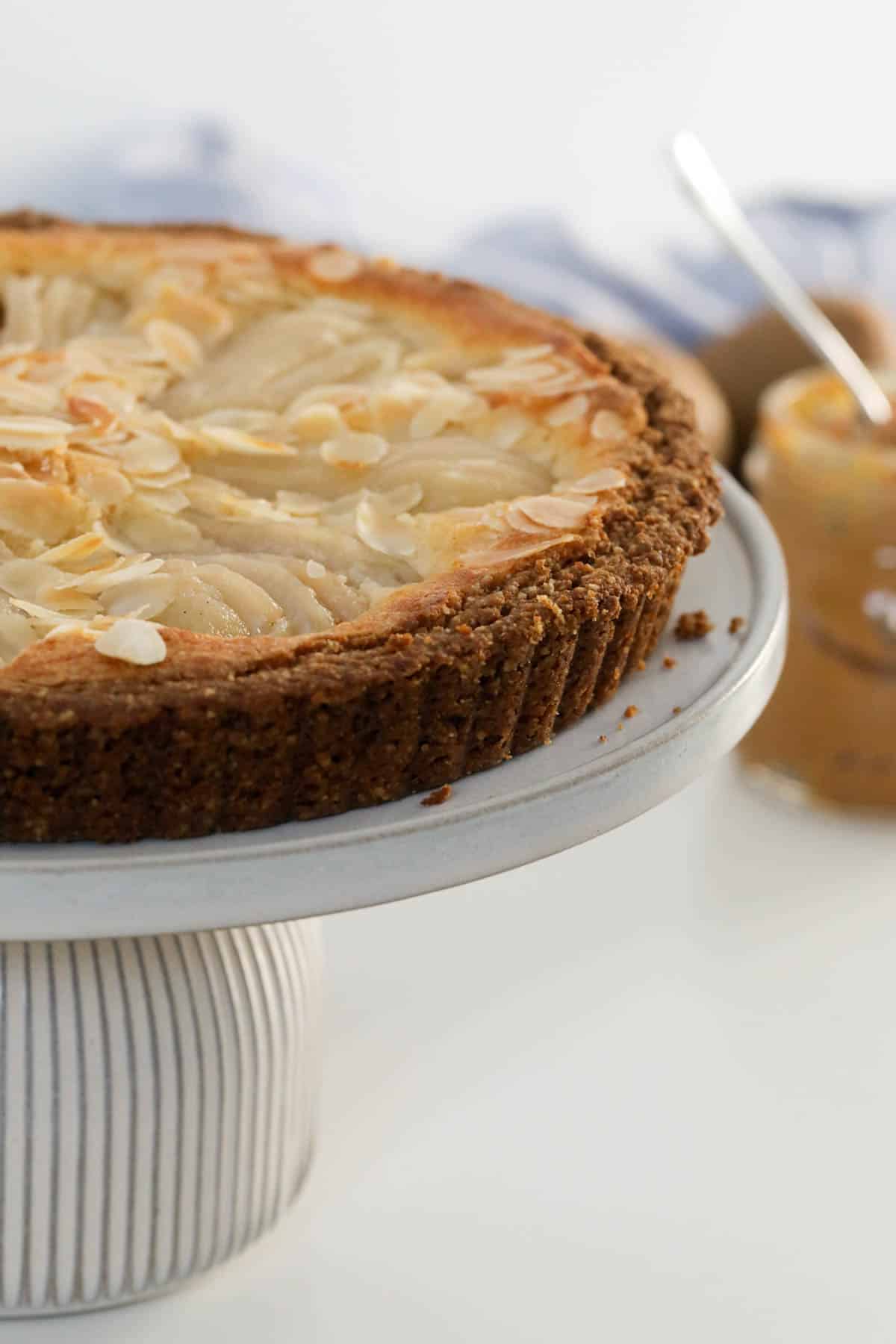 Pear and almond tart served on a cake stand.