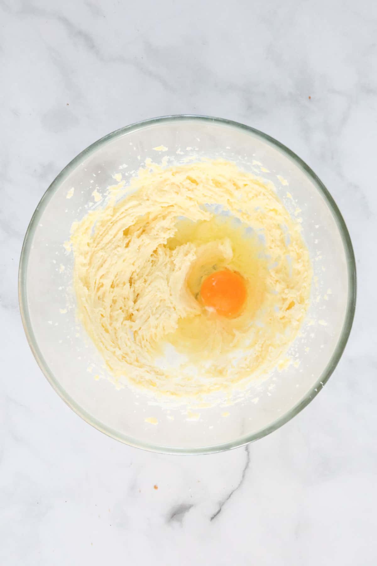 Creamy butter and sugar, with an egg added to the mixing bowl.