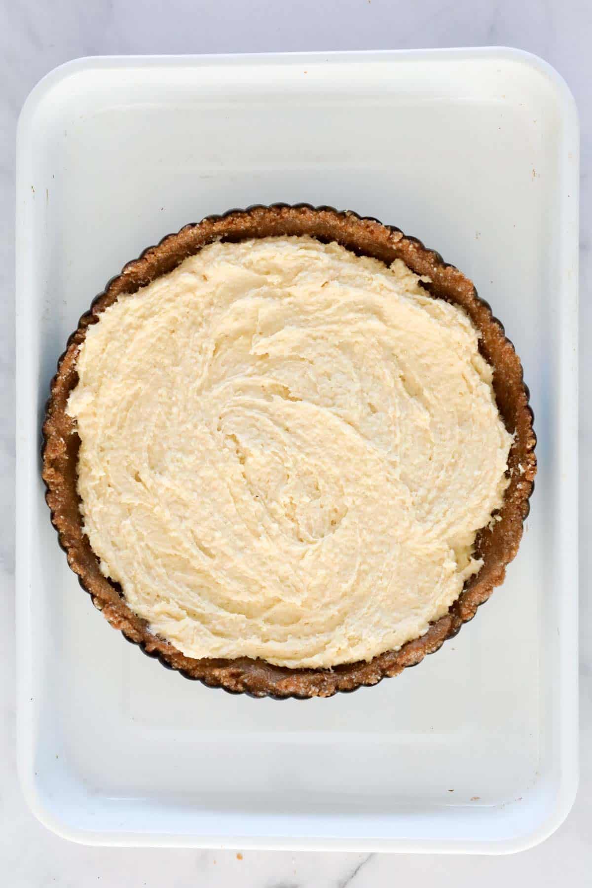 Almond cream spread over biscuit base in tart tin.