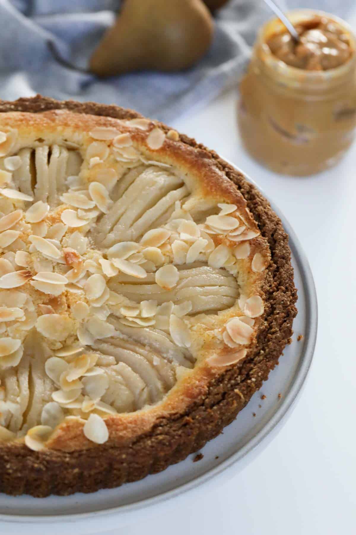 A golden pear tart with flaked almonds sprinkled over the top.