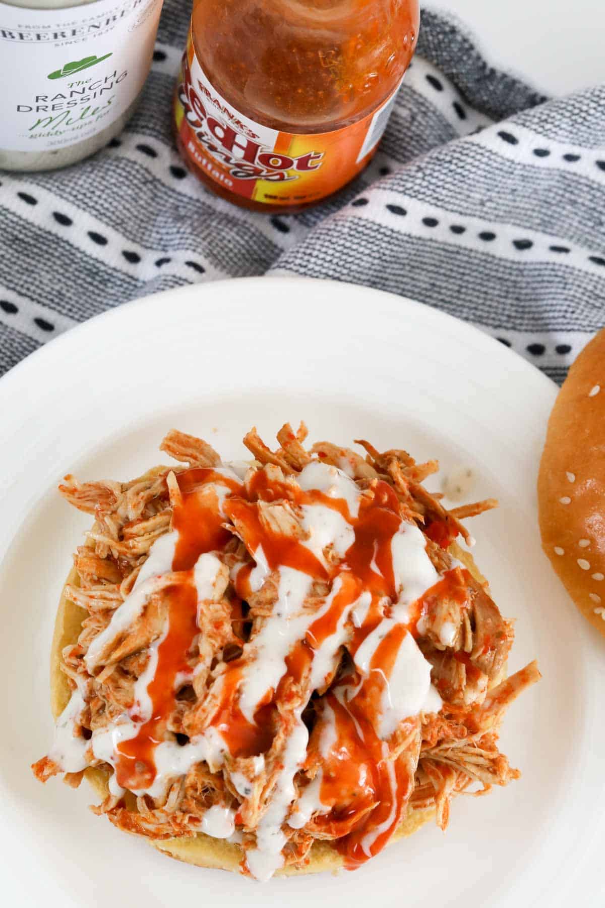 An overhead shot of ranch dressing and spicy sauce on shredded chicken.