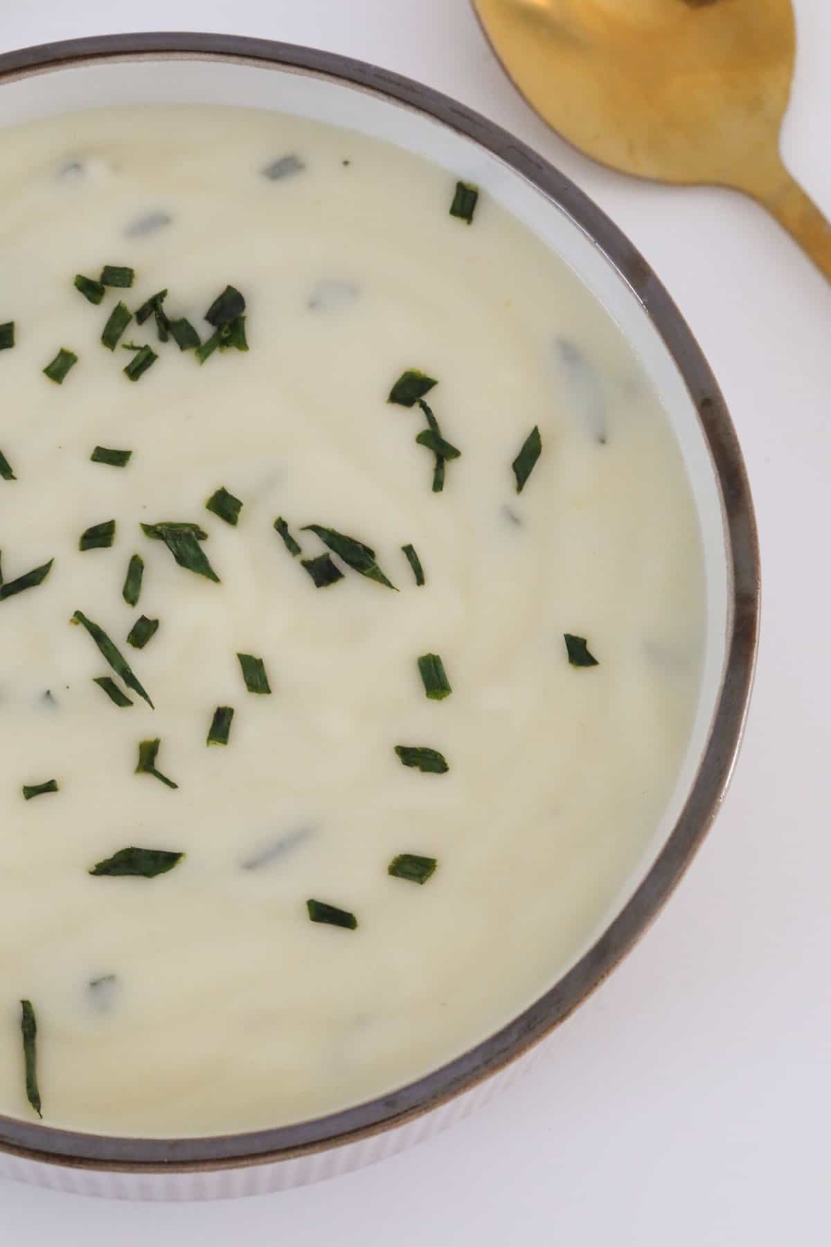 An overhead shot of chives sprinkled on creamy soup in a bowl.