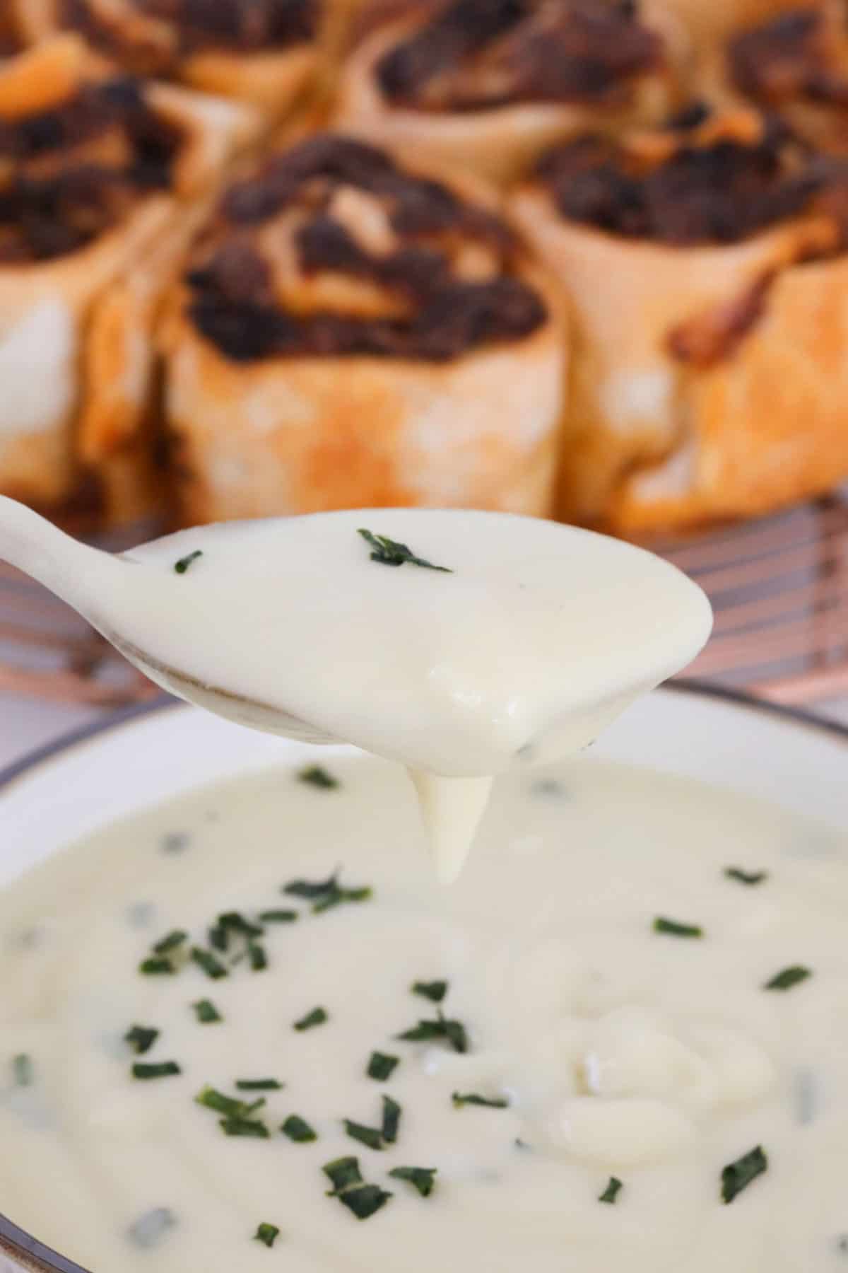 A spoonful of creamy potato soup held above a bowl.
