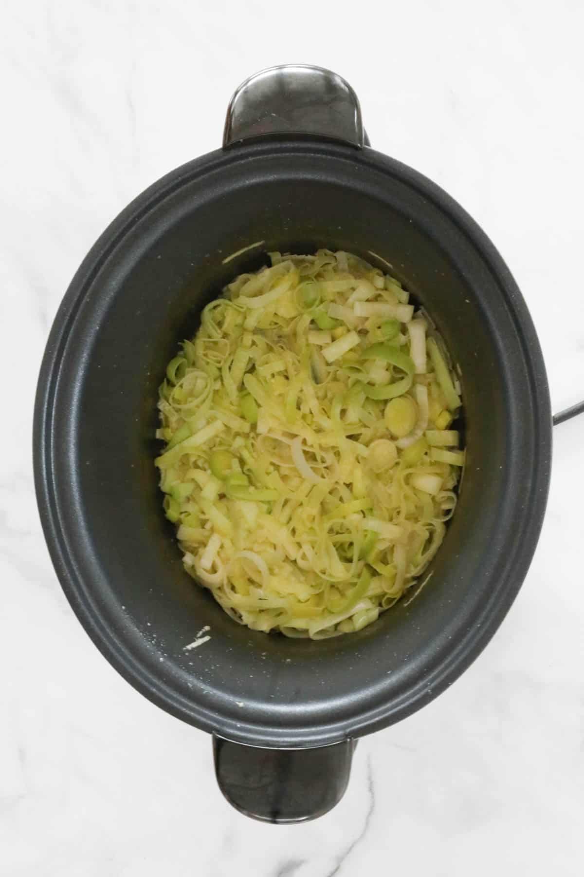 Leeks and garlic sauteing in a slow cooker.