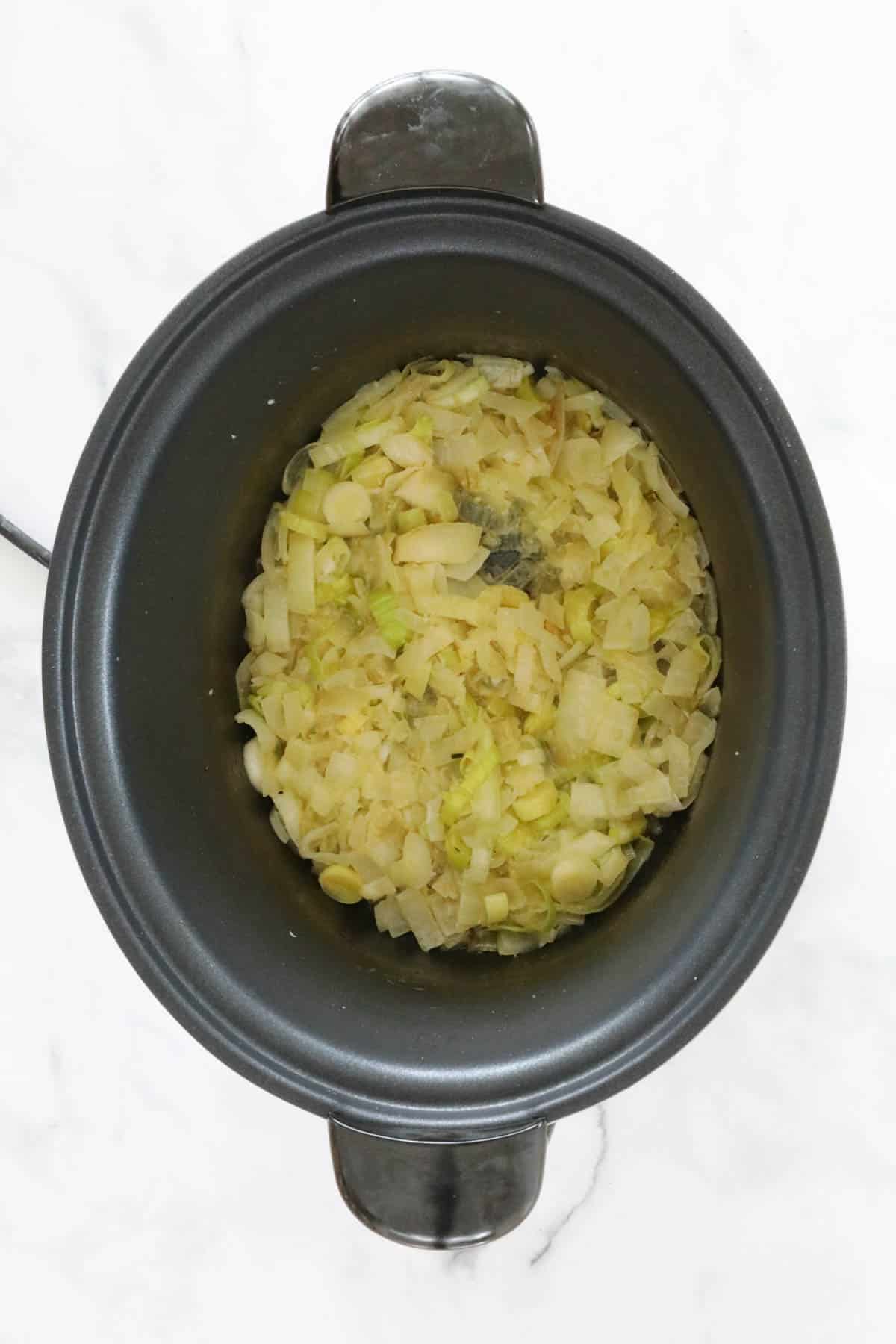 Sauteed sliced leek, onion and garlic placed into a slow cooker bowl.