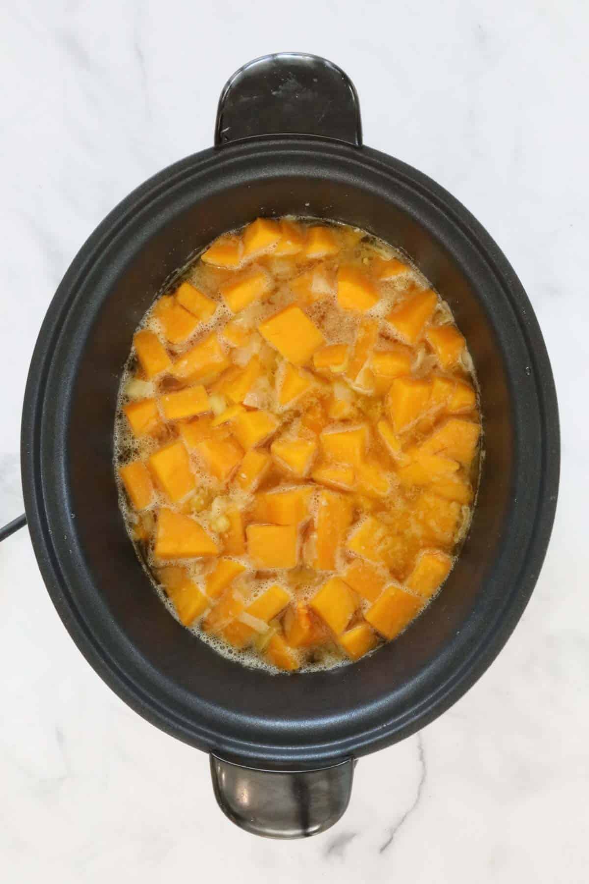 Cooked pumpkin, leek and stock in a slow cooker.