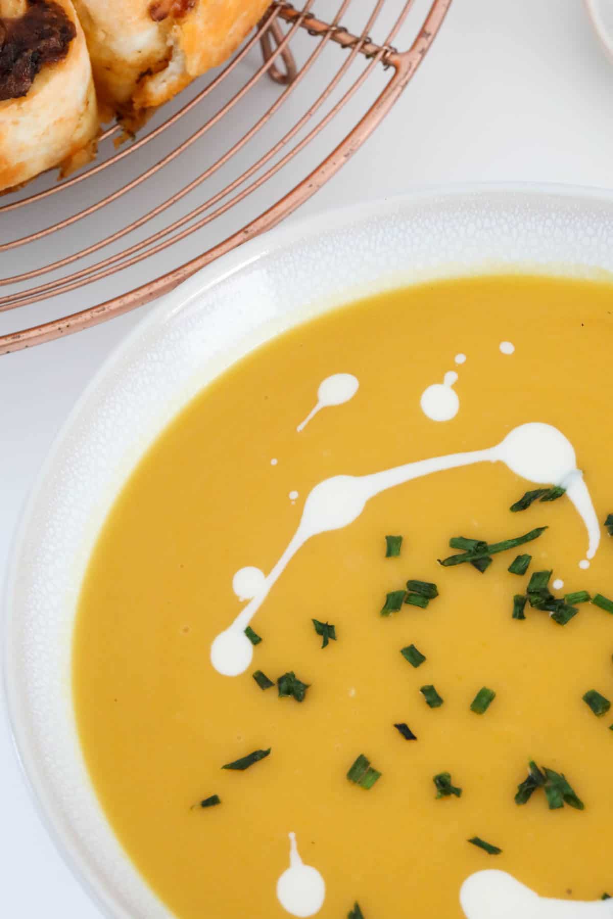 An overhead shot of a white bowl filled with pumpkin soup.