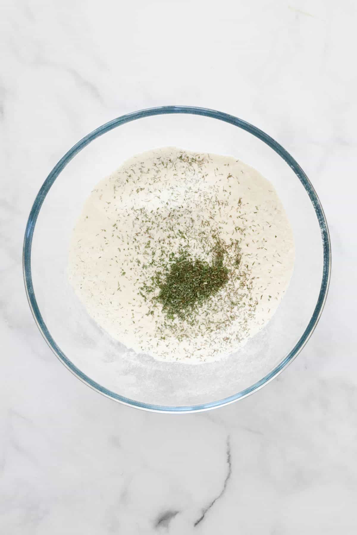 Flour and dried herbs in a mixing bowl.