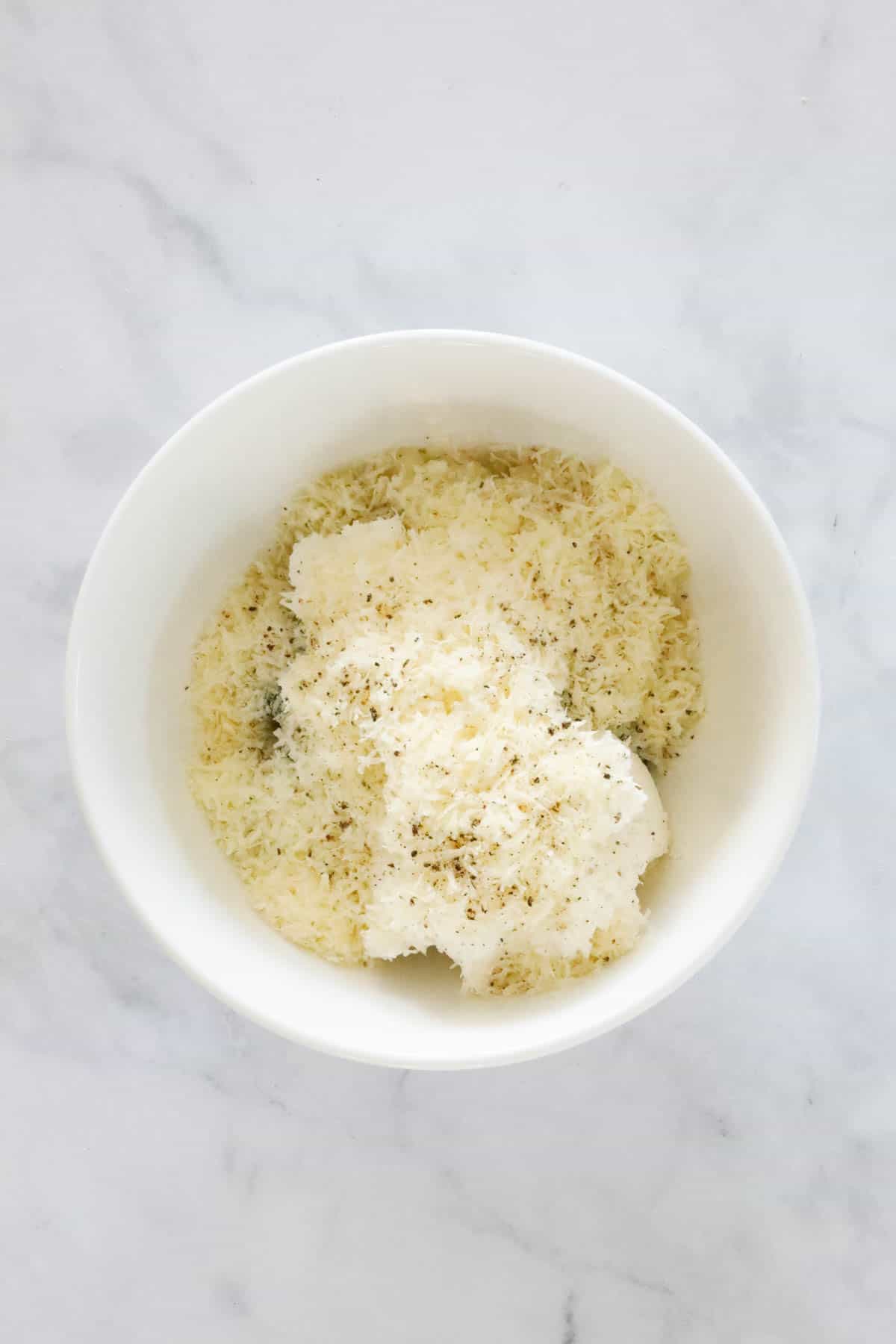 Ricotta and parmesan in a white mixing bowl.