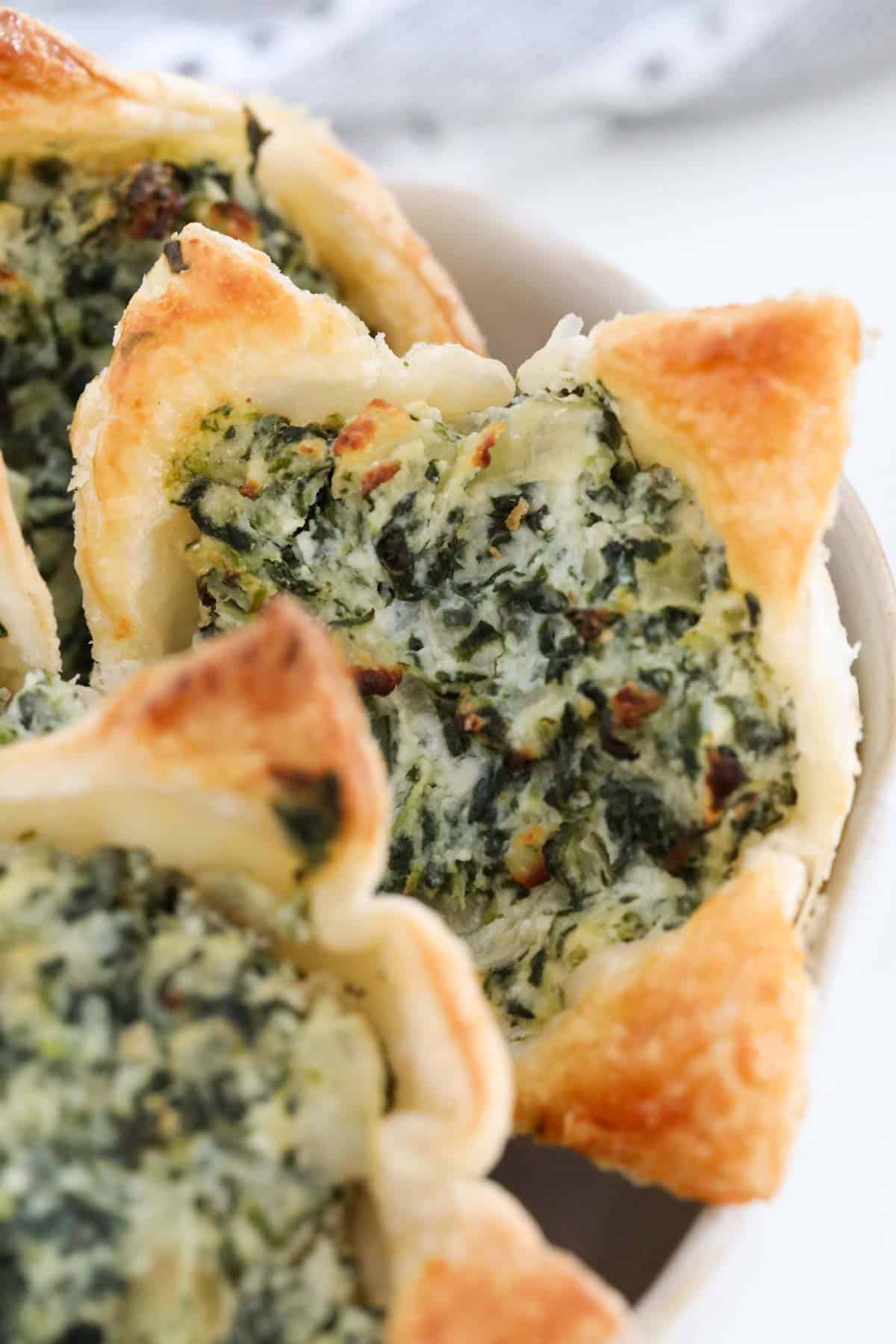 A close up of ricotta and spinach puff pastry tarts.