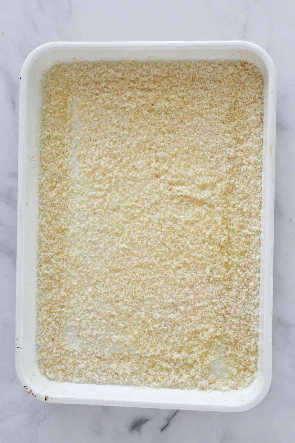Panko crumbs spread out in a bakinng dish.