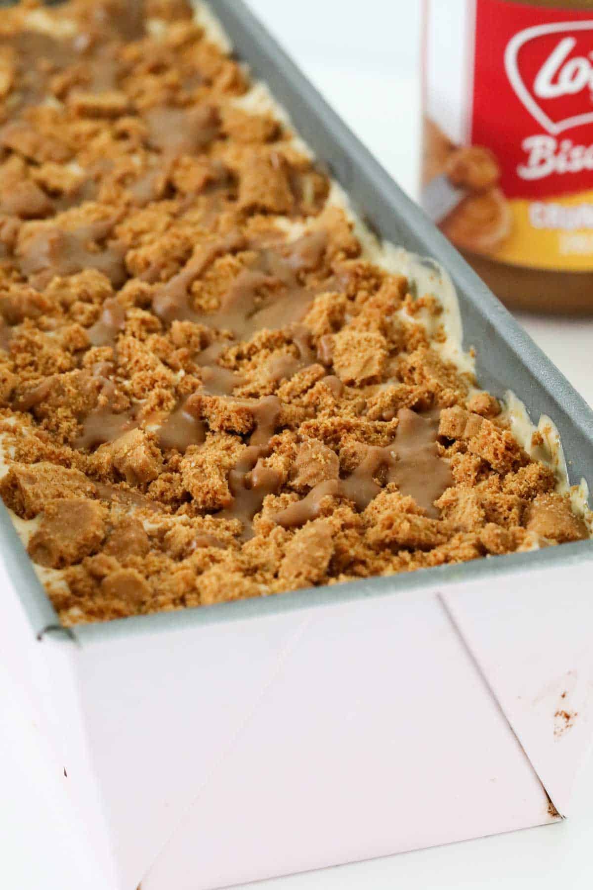 Crumbled biscuits and Biscoff spread over the top of ice cream in a loaf tin.
