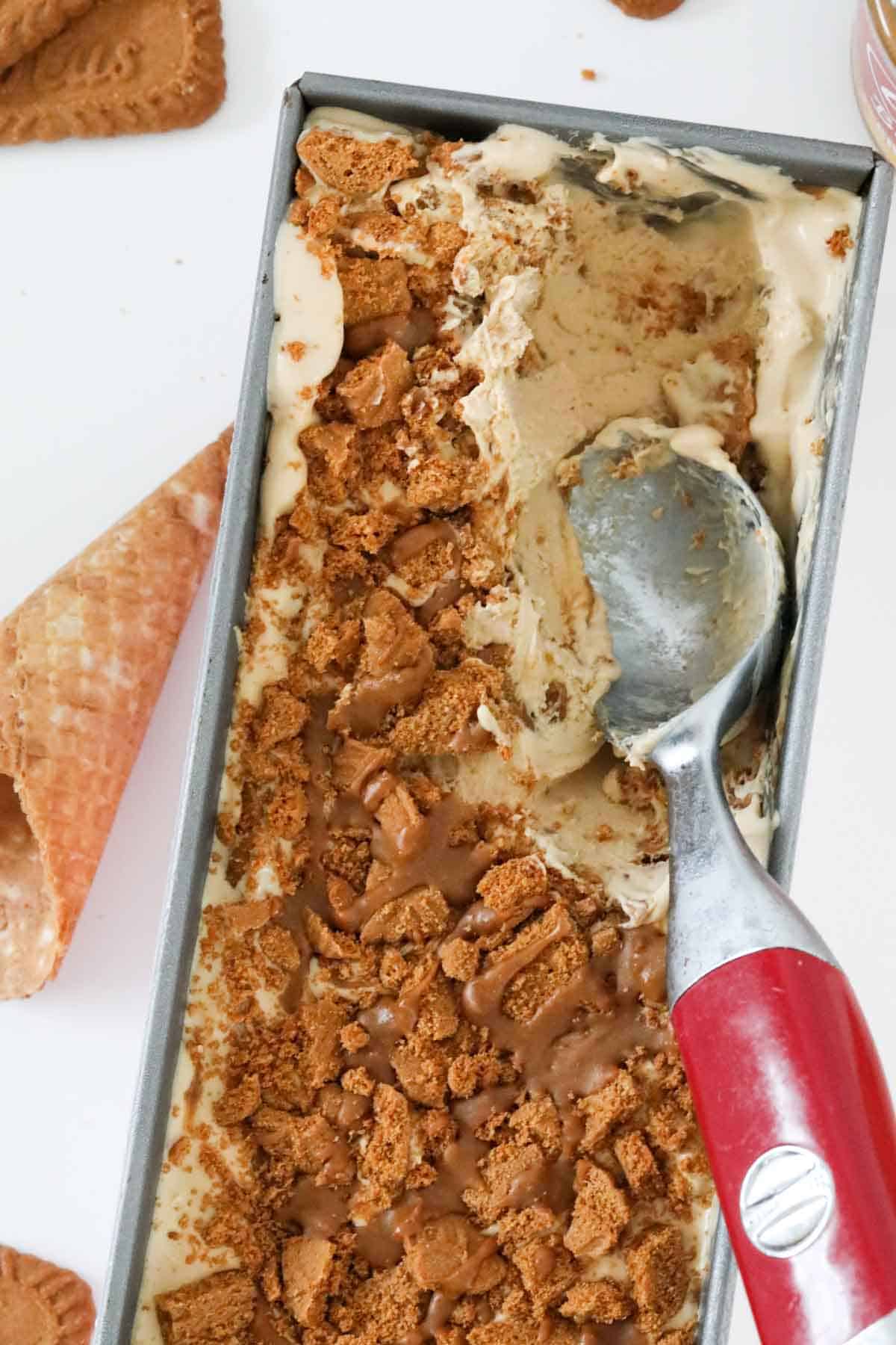 An ice cream scoop in a tray of Biscoff Ice Cream.