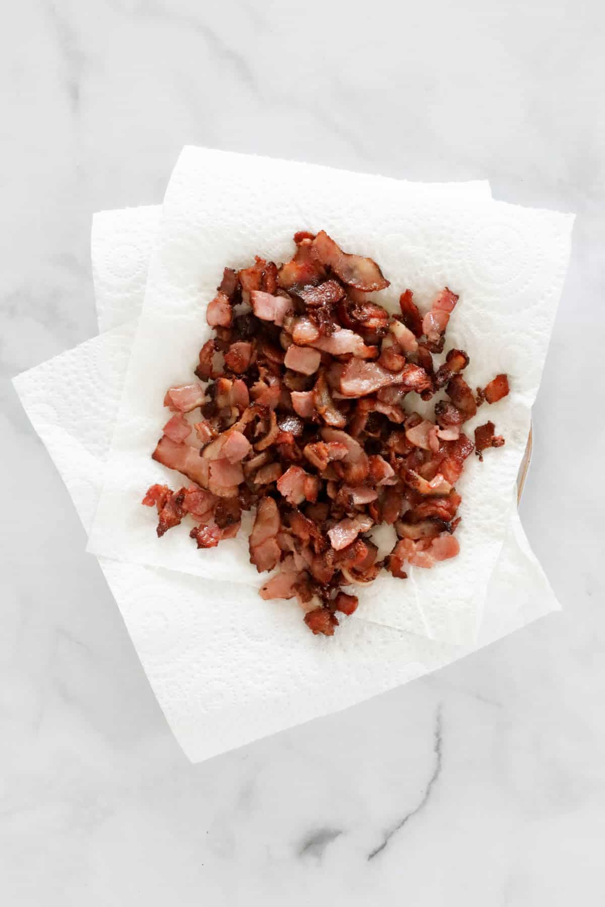 Crispy bacon pieces on kitchen paper towel.