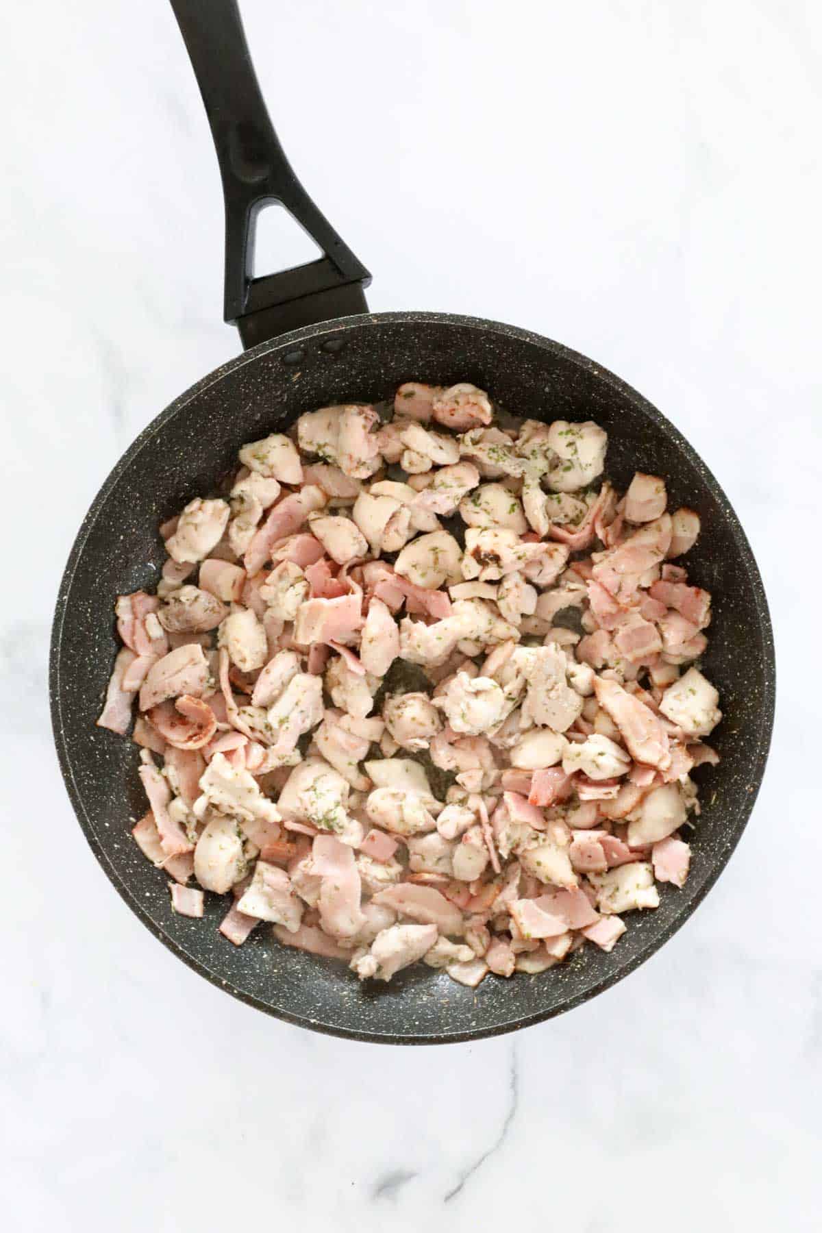Browning chicken pieces in a frying pan.