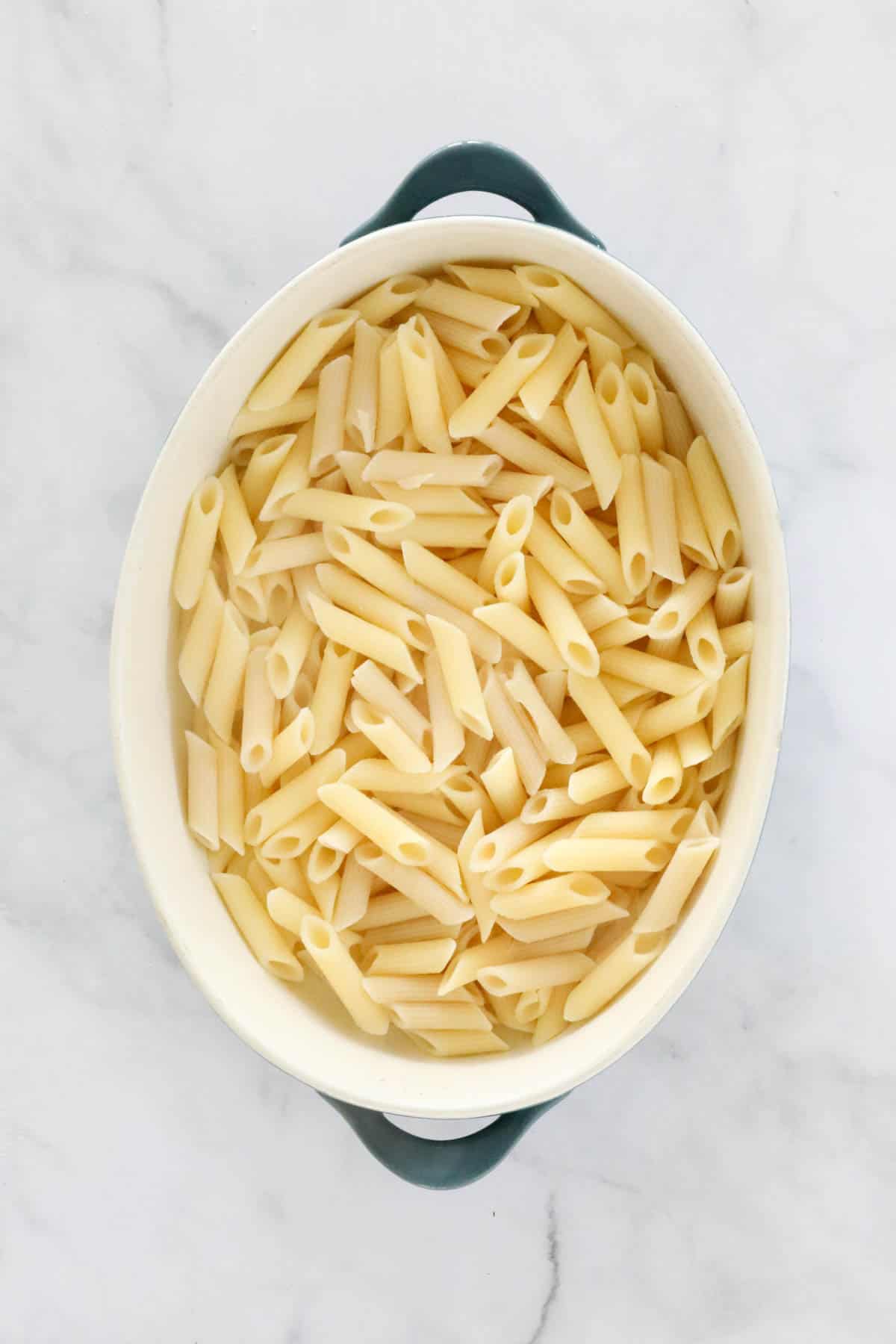 Cooked and drained penne placed in a large baking dish.