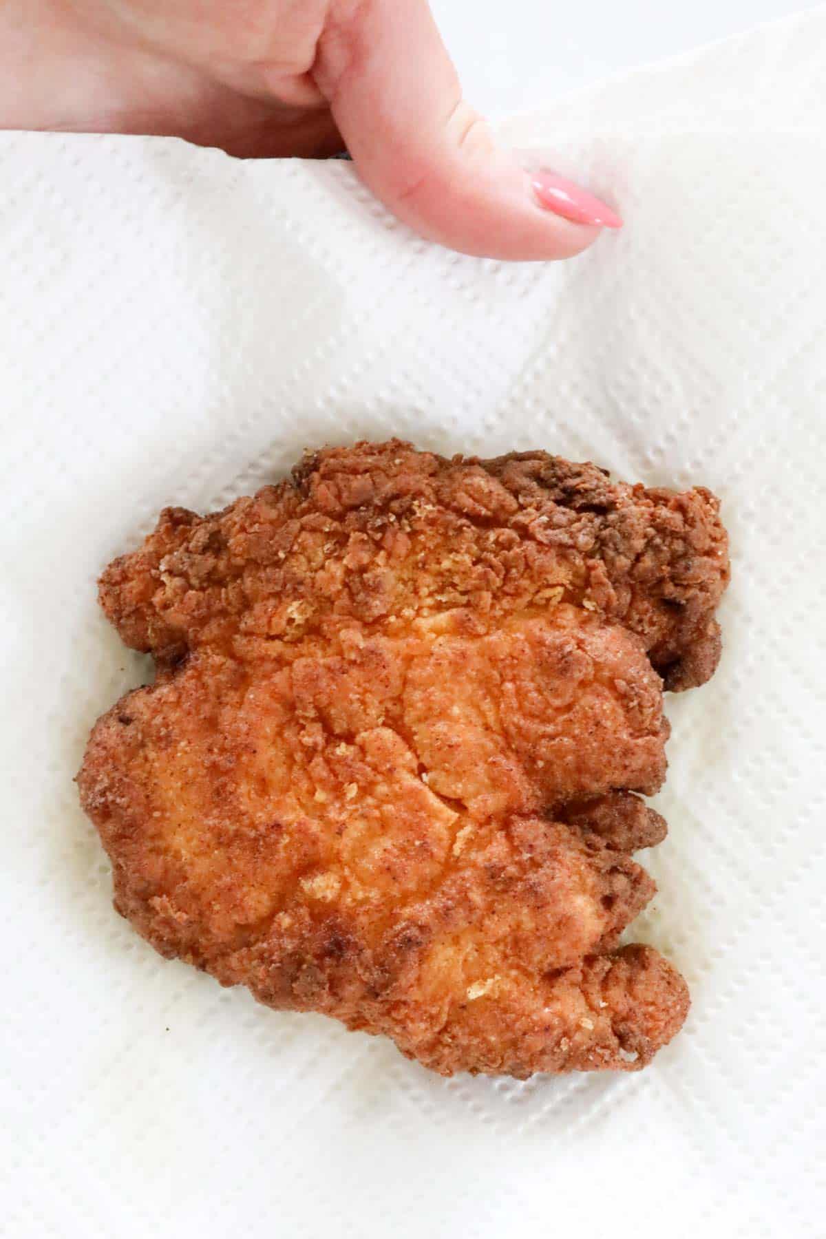 A super crispy fried chicken thigh on paper towel.