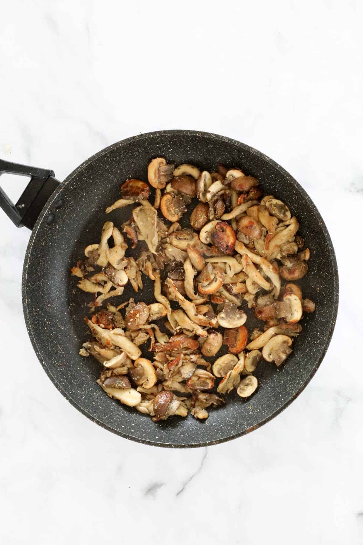 Golden mushrooms frying in a pan.