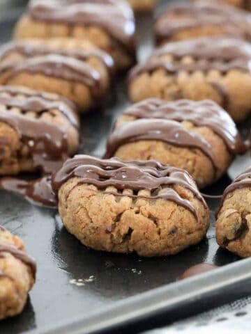 A tray of baked sticky date cookies drizzled with chocolate.
