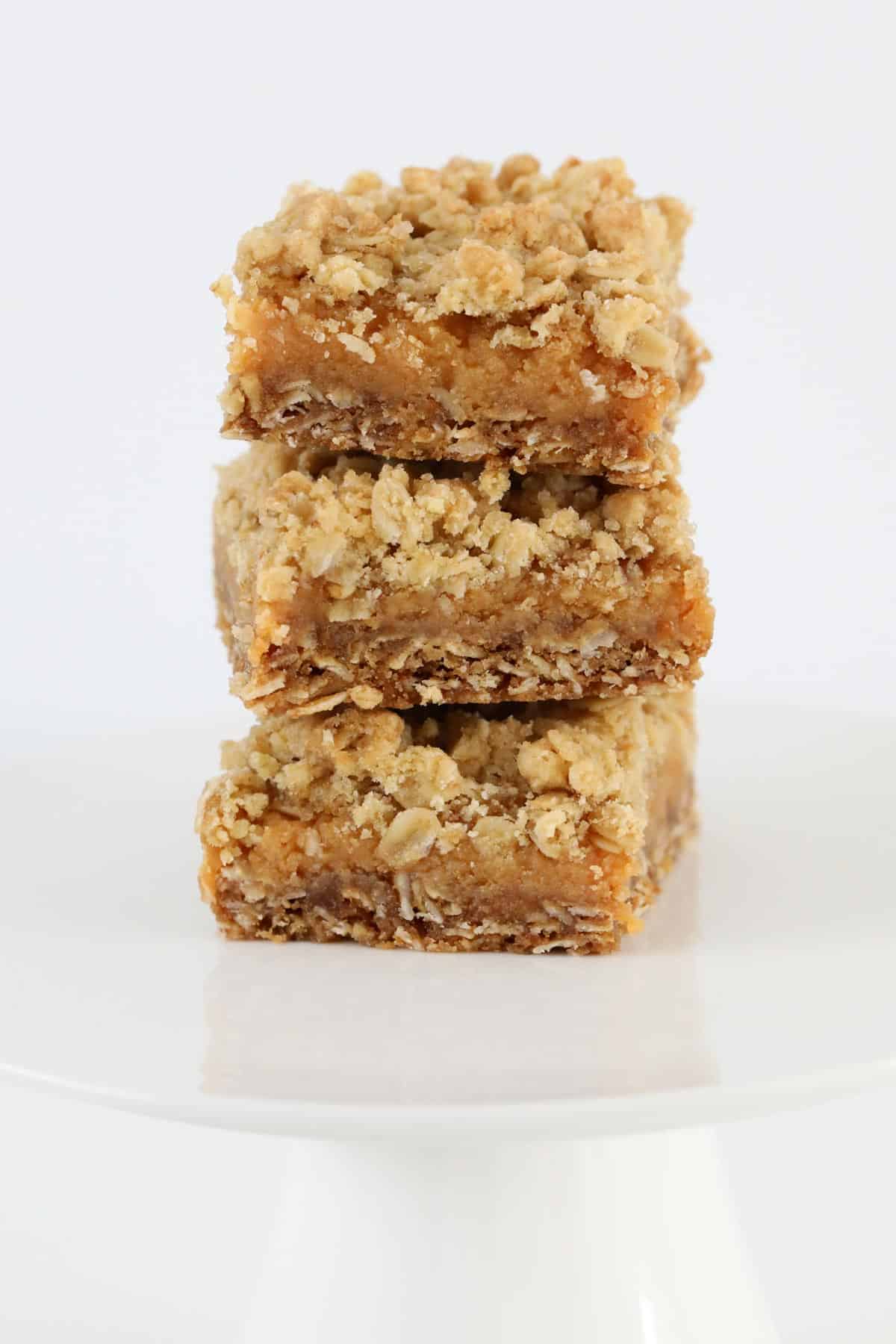 Three squares of caramel crumble slice stacked together.