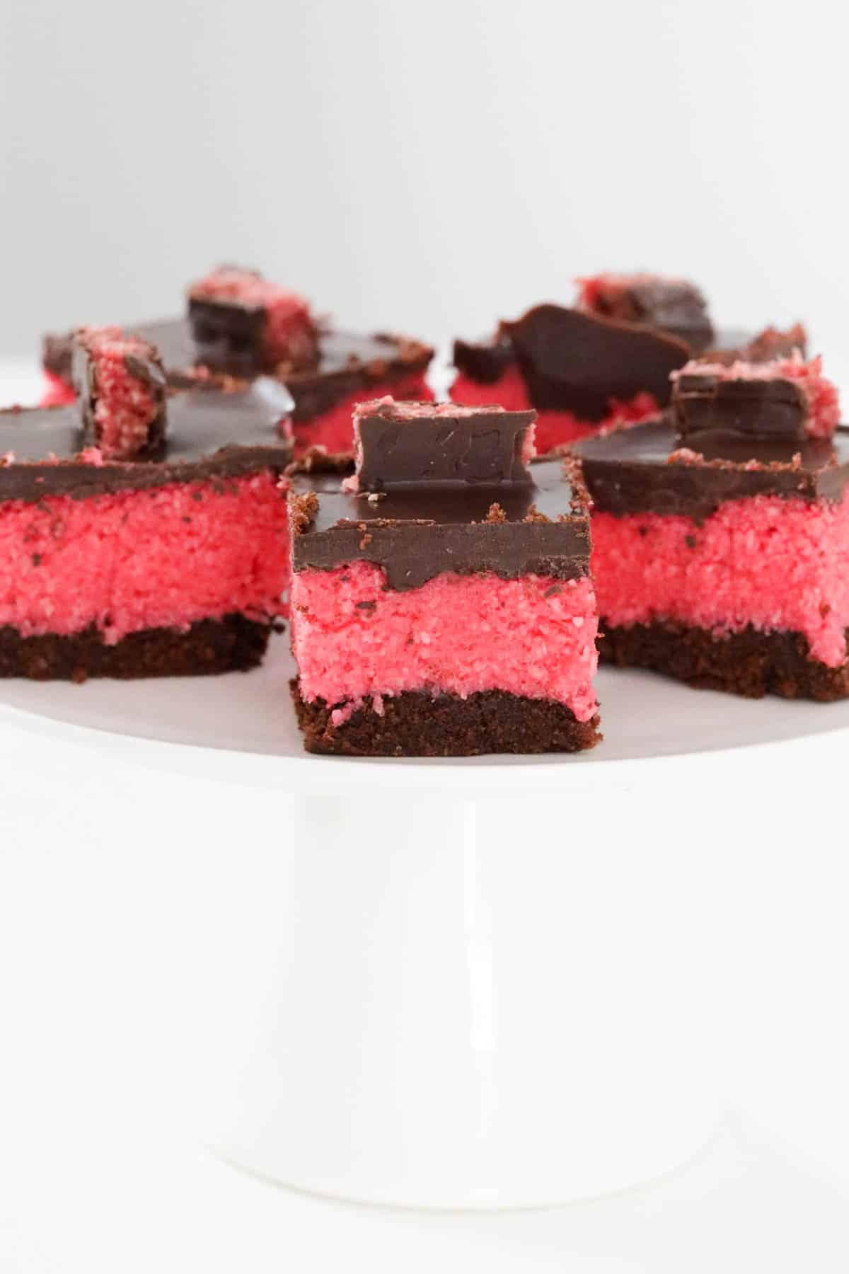 Squares of cherry ripe slice on a white cake stand.
