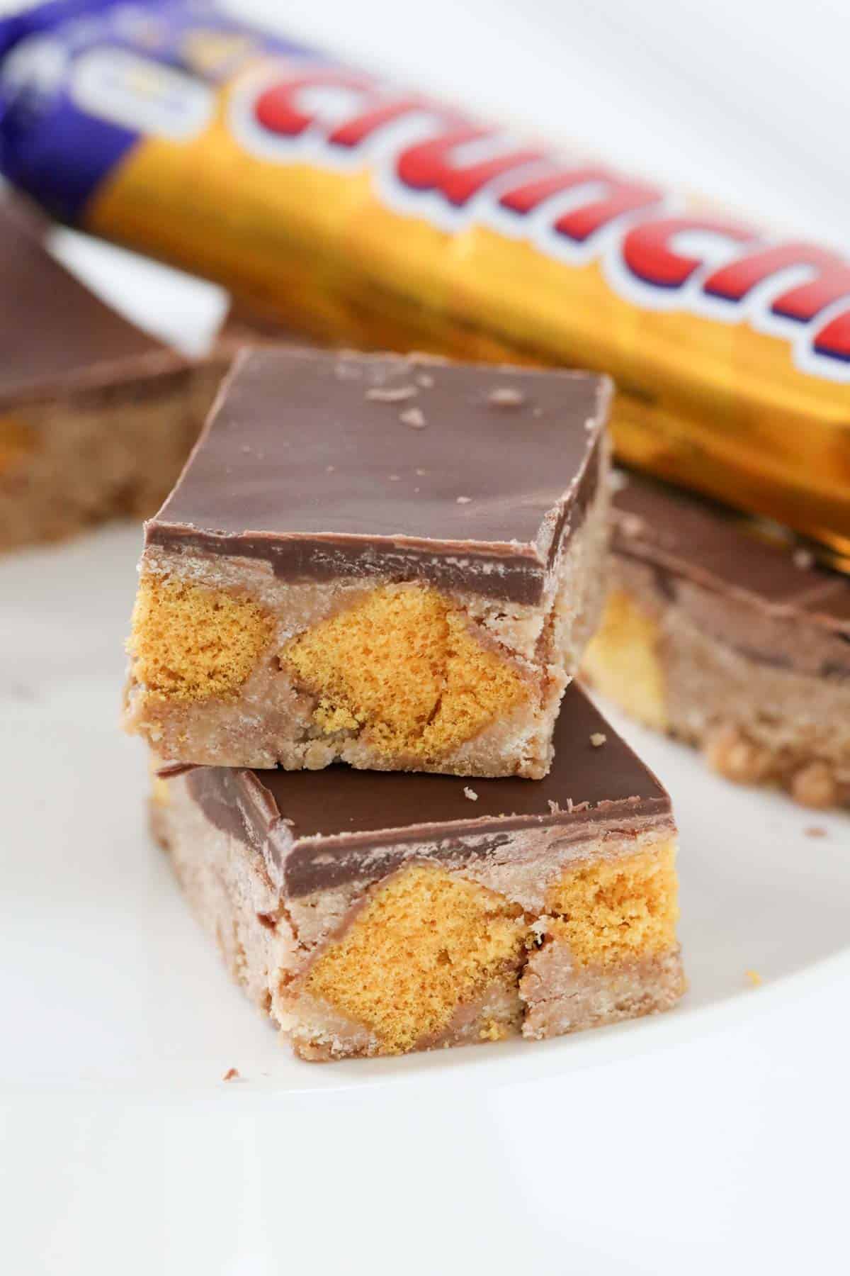 Squares of Crunchie slice in front of a Crunchie bar.