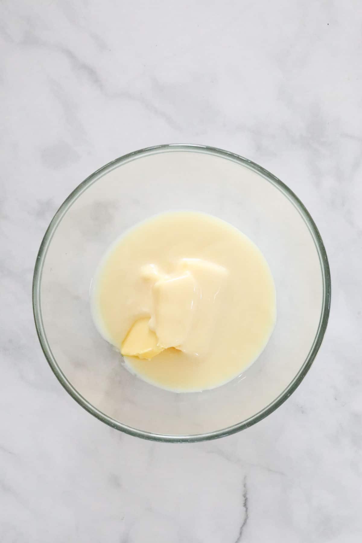 Butter and condensed milk in a glass bowl.